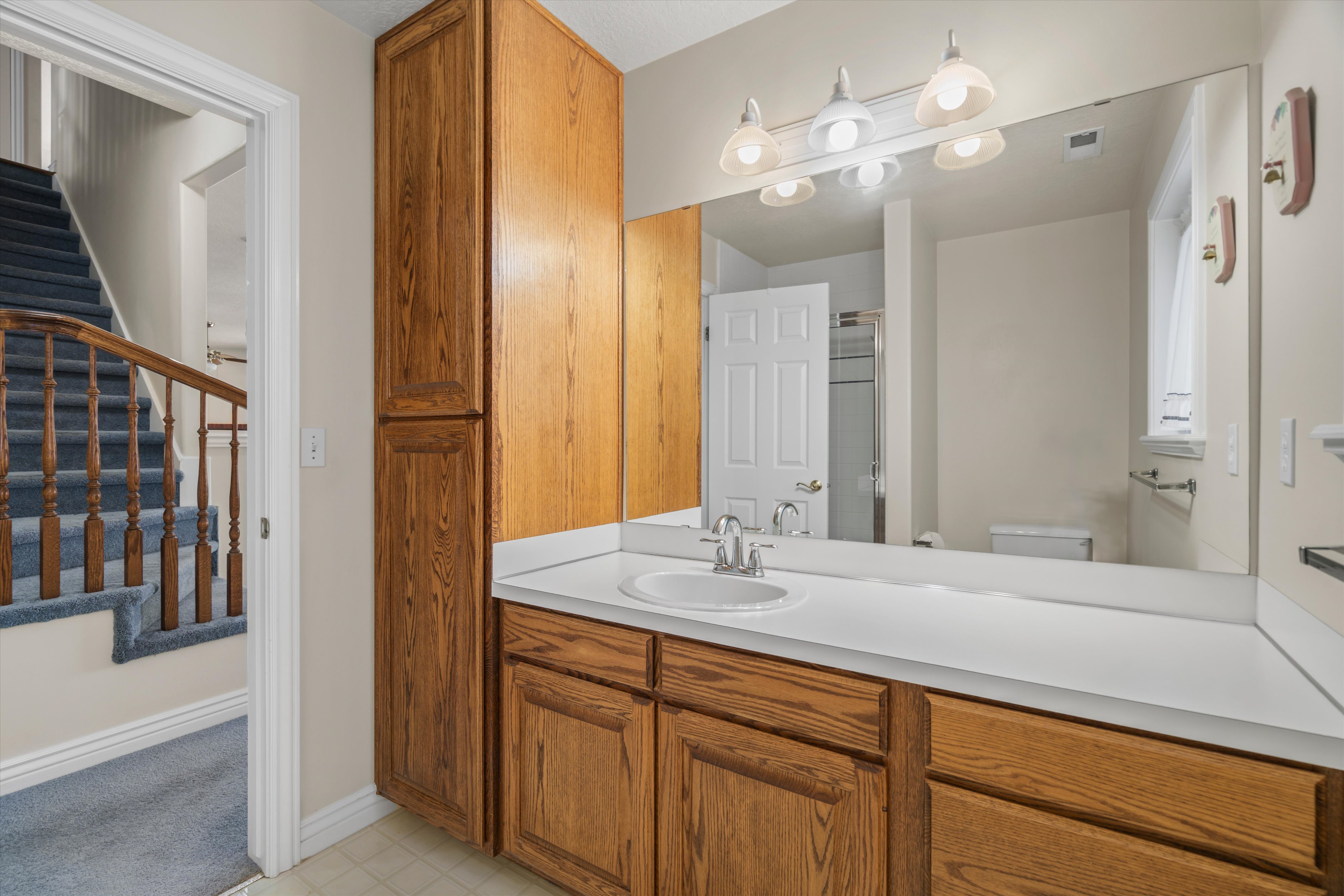 Bathroom vanity featuring wood cabinetry, a white countertop, and an integrated sink