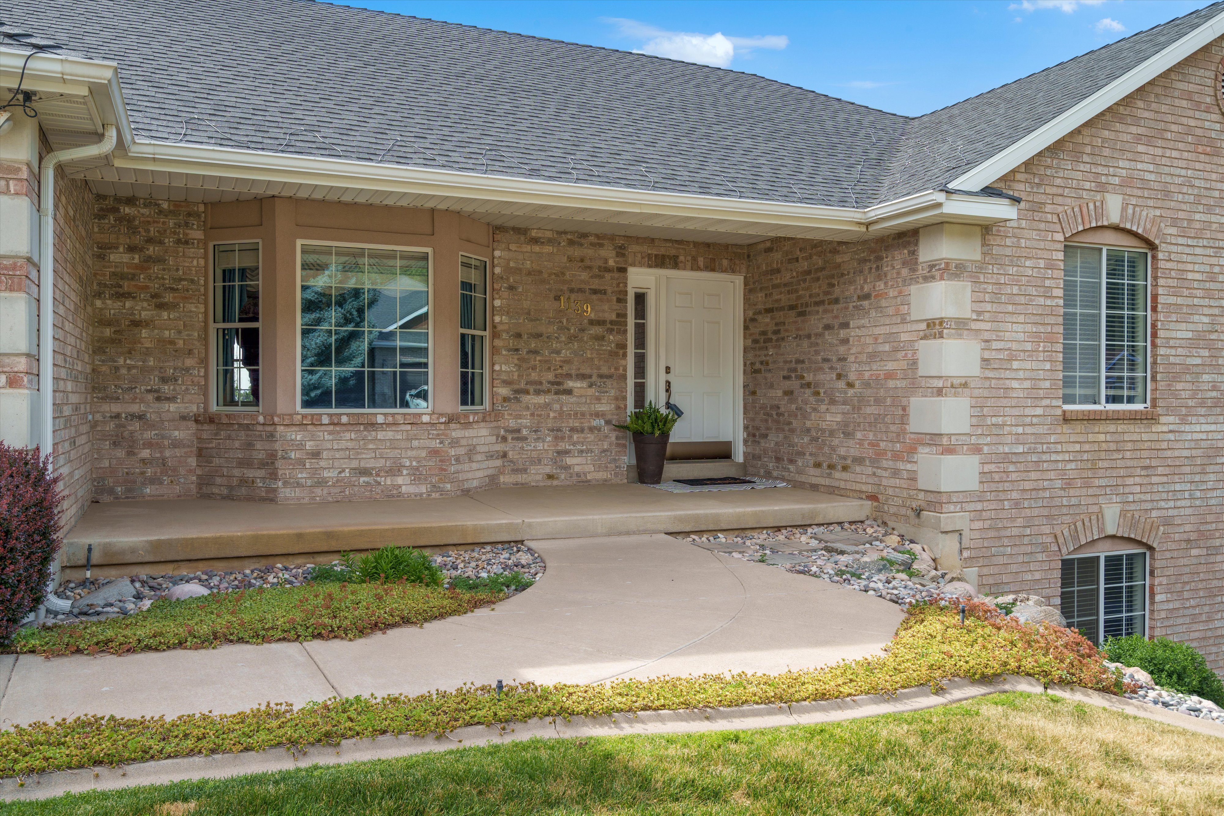 Brick exterior with a prominent bay window, a covered entry, and a concrete walkway