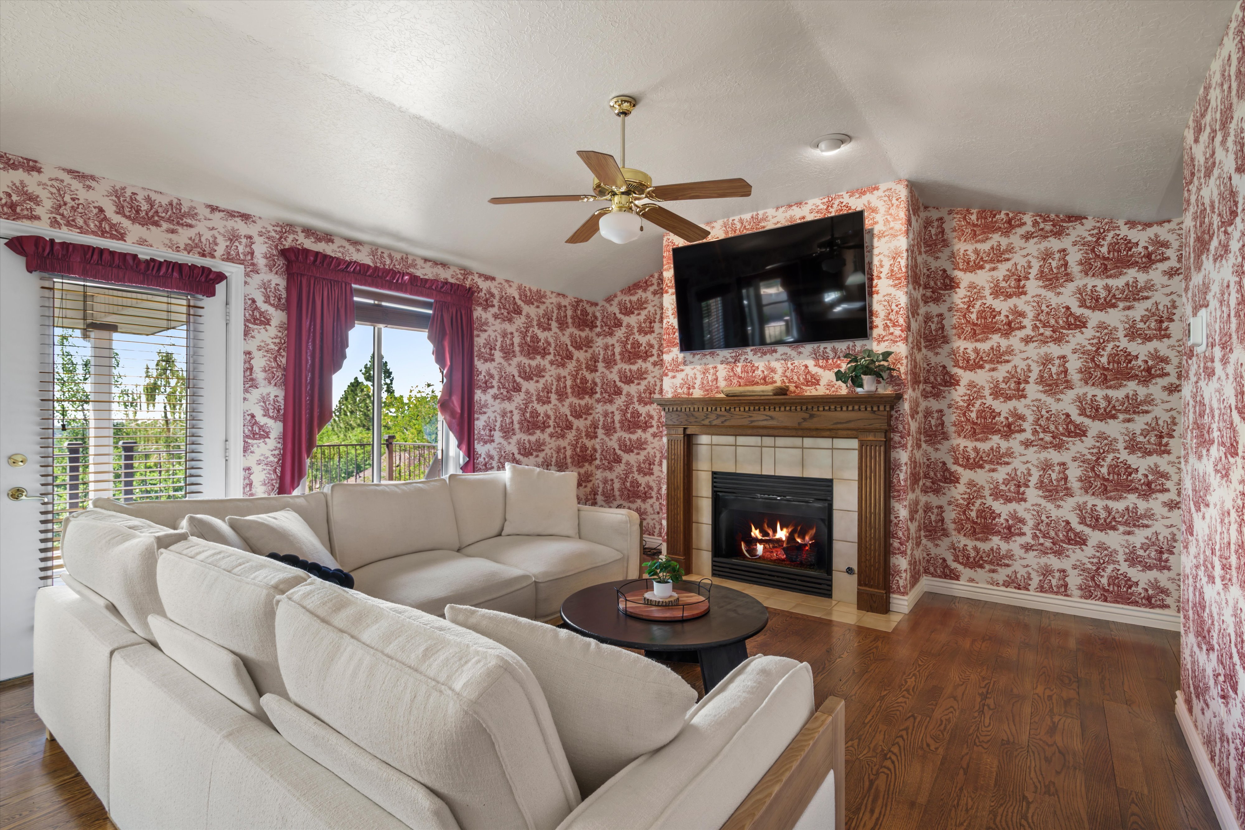 Living area featuring wood-finish flooring, a fireplace with a wood mantel and tile surround, and vaulted ceilings