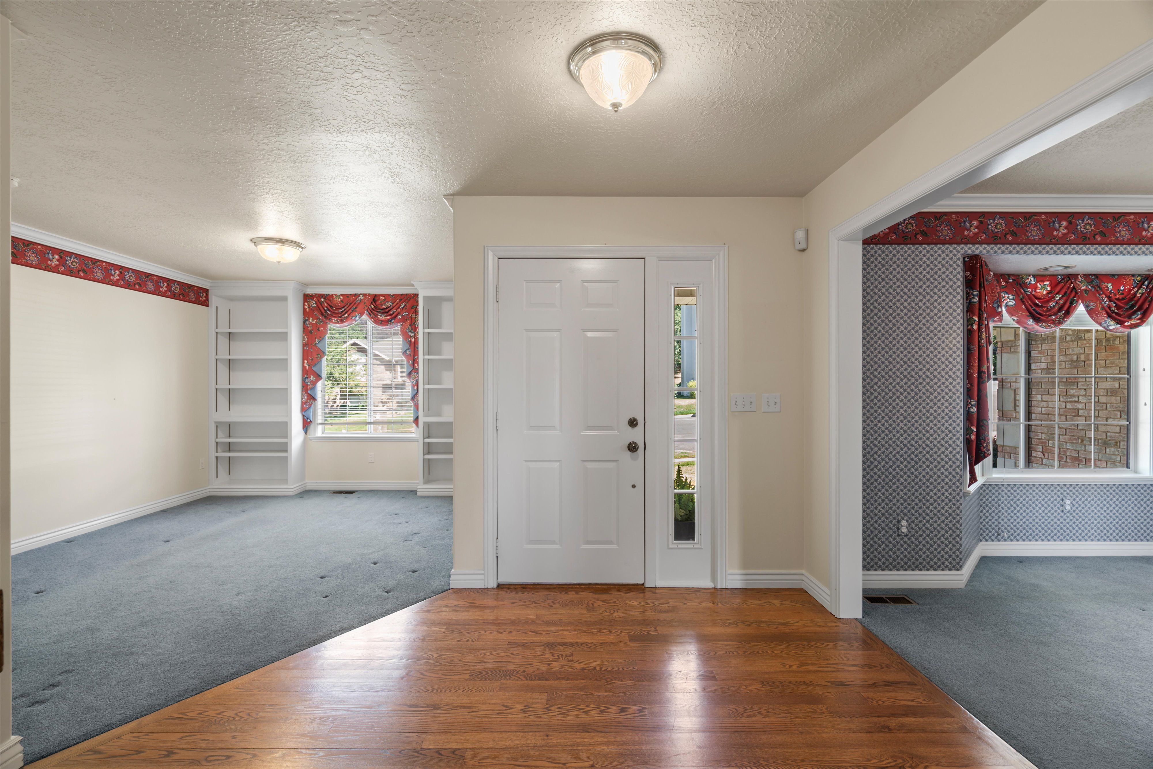 Entryway featuring wood-finish flooring, a paneled front door with a sidelight, and flush-mount lighting