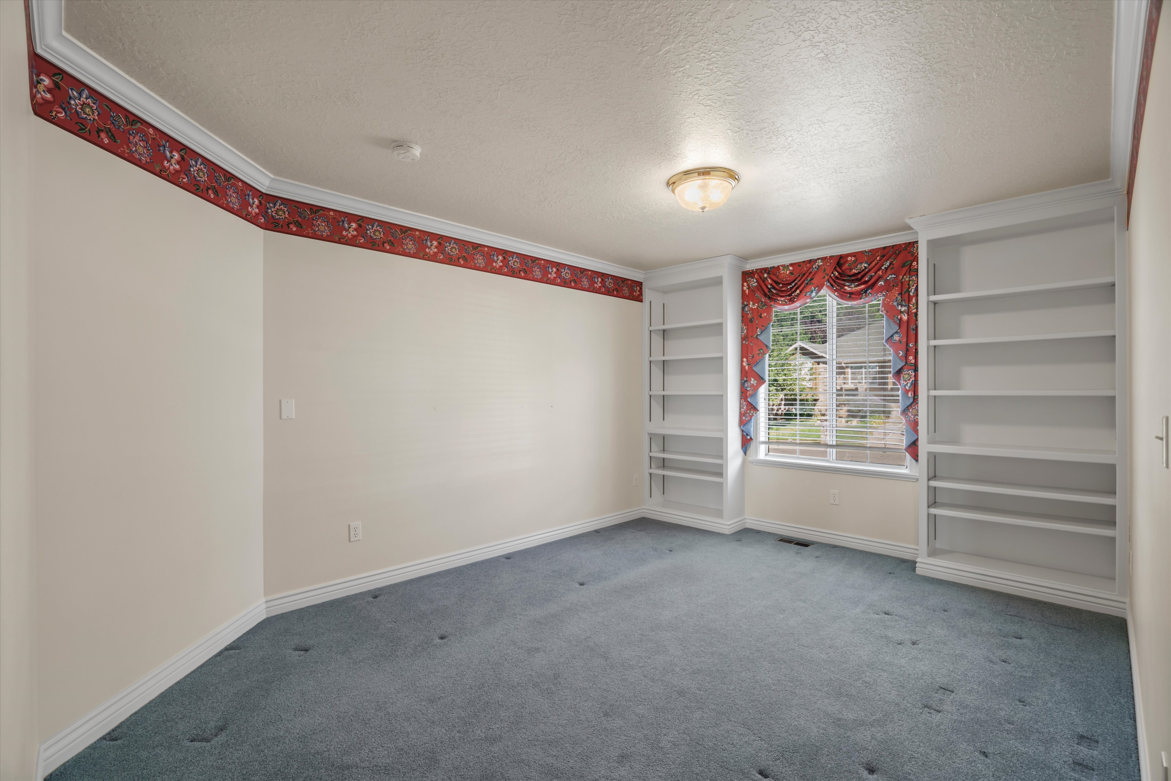 Room featuring built-in shelving, a window with horizontal blinds, and a flush mount ceiling light