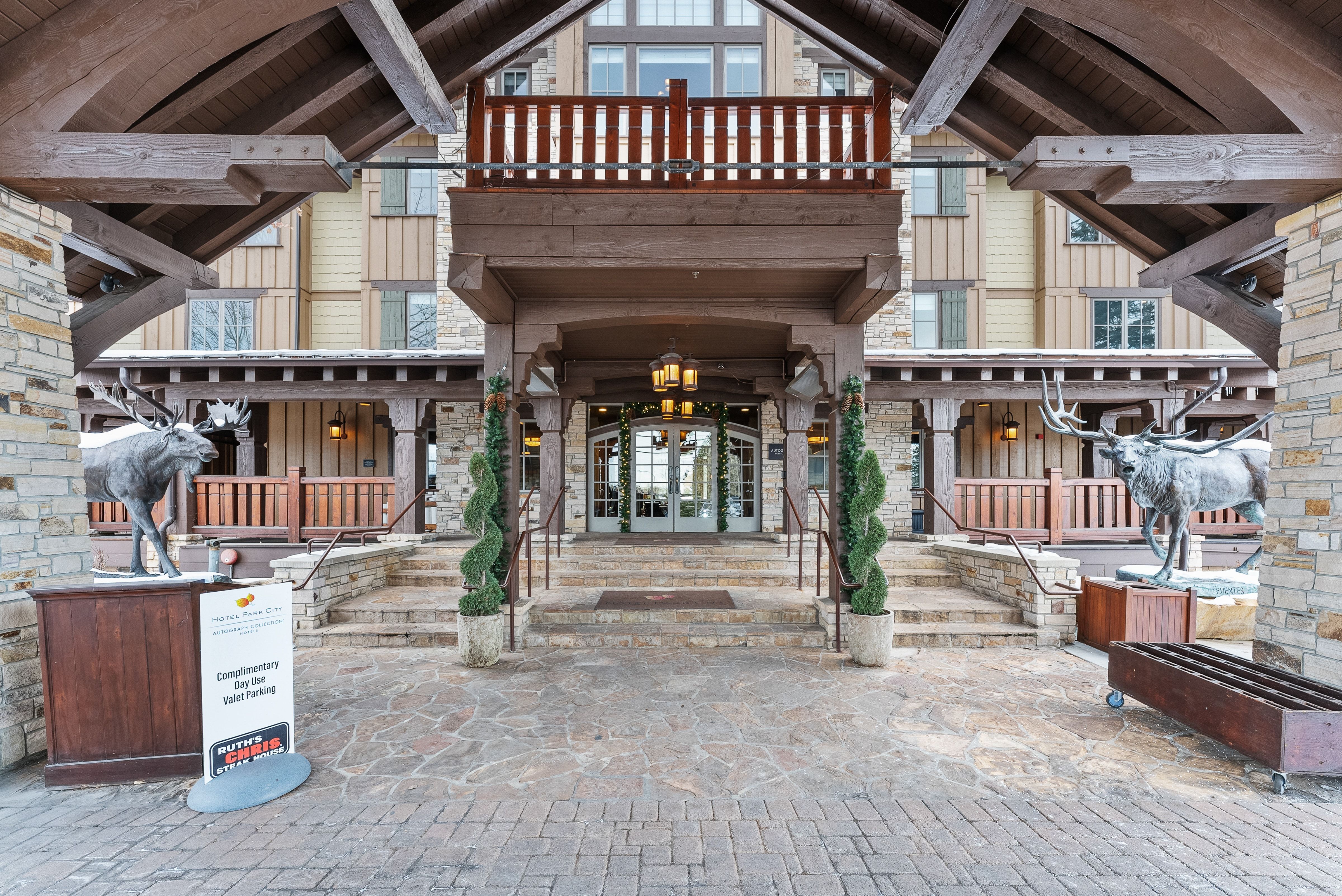Stone and timber facade featuring a covered entryway with decorative lighting