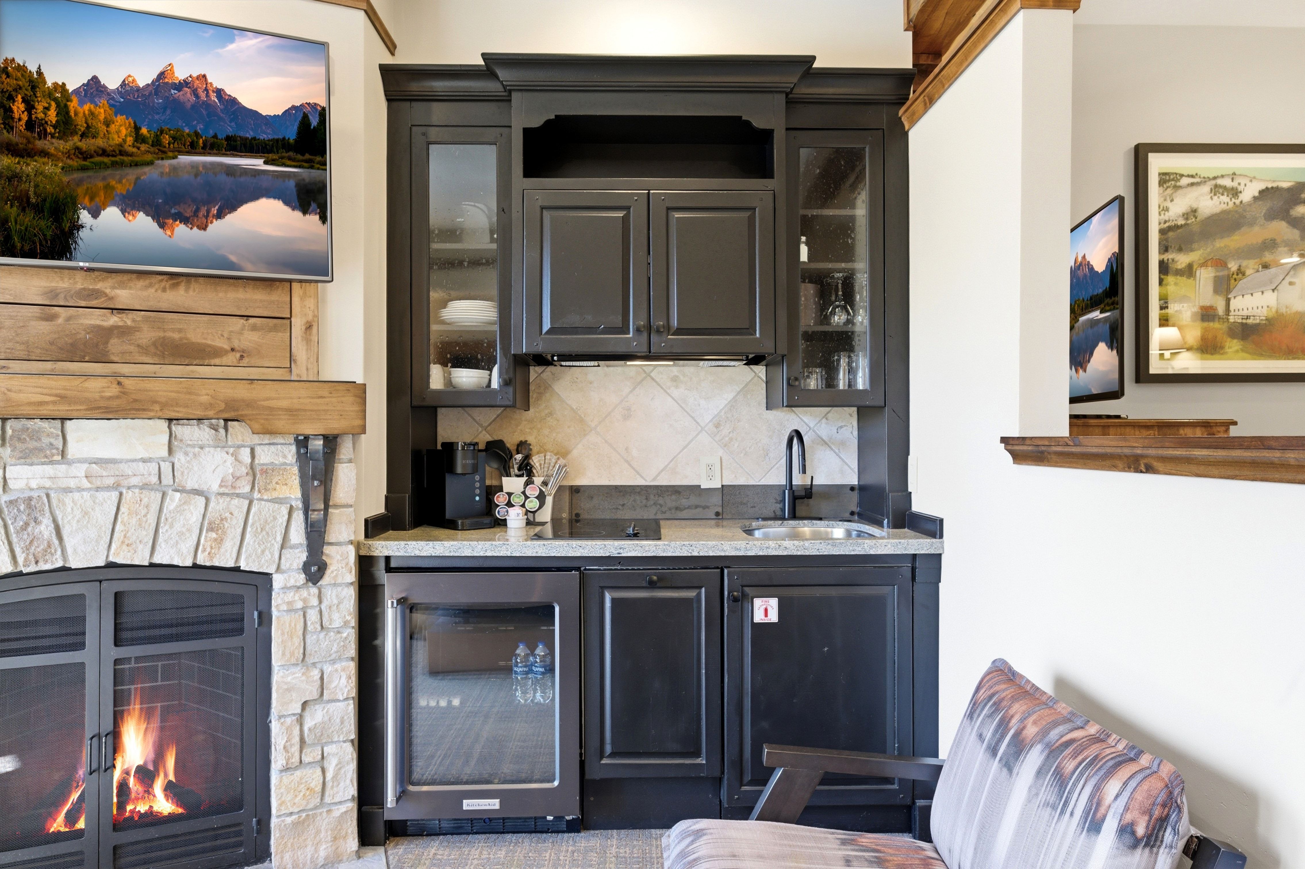 Built-in wet bar with dark cabinetry, integrated beverage refrigerator, and stone countertop