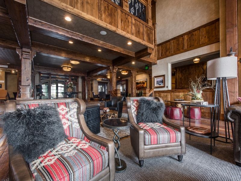 Spacious common area featuring exposed wood beams and columns, wood-paneled walls, a carpeted floor, and recessed lighting