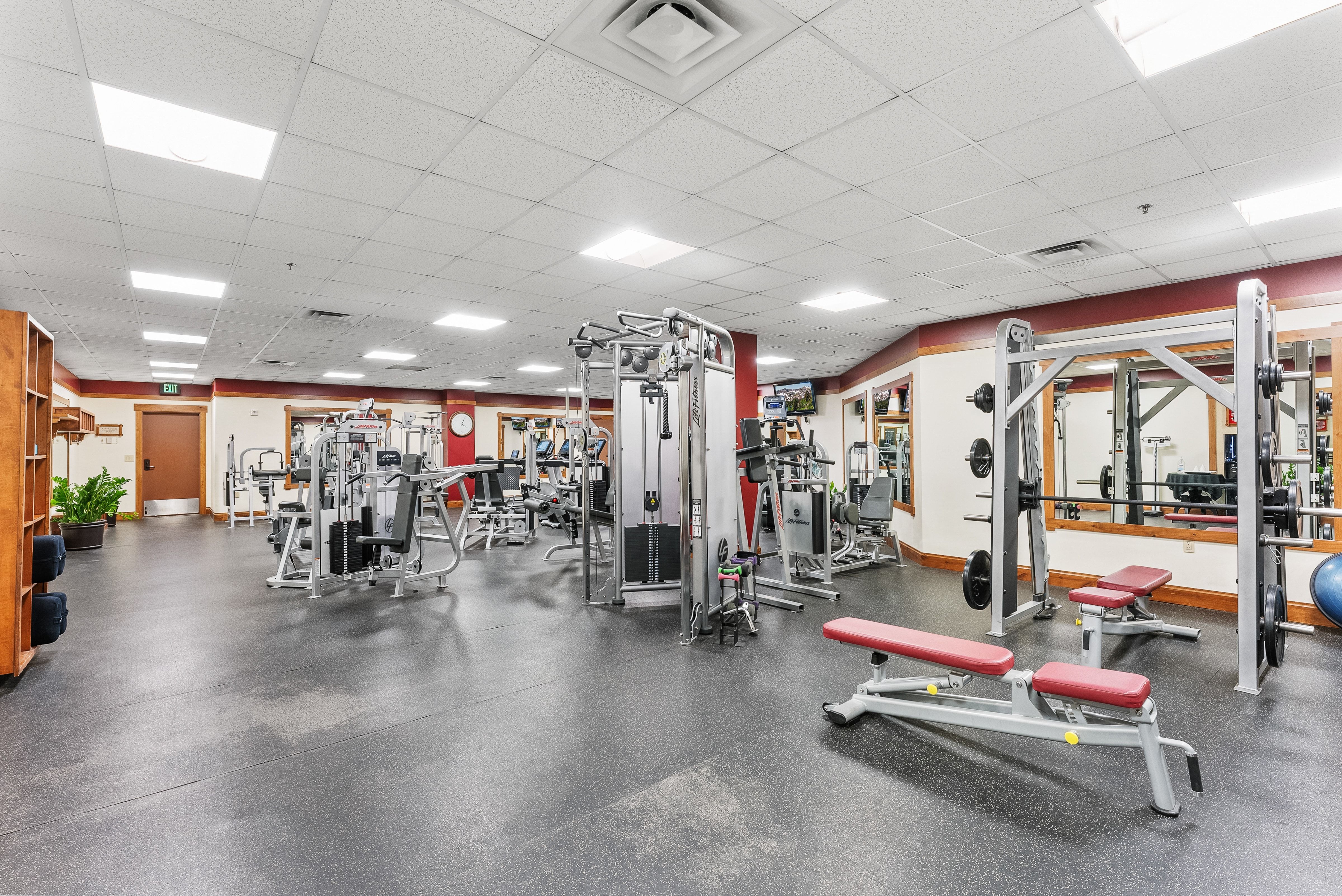 Fitness center featuring various exercise equipment, rubber flooring, recessed lighting, mirrors, and wood trim details