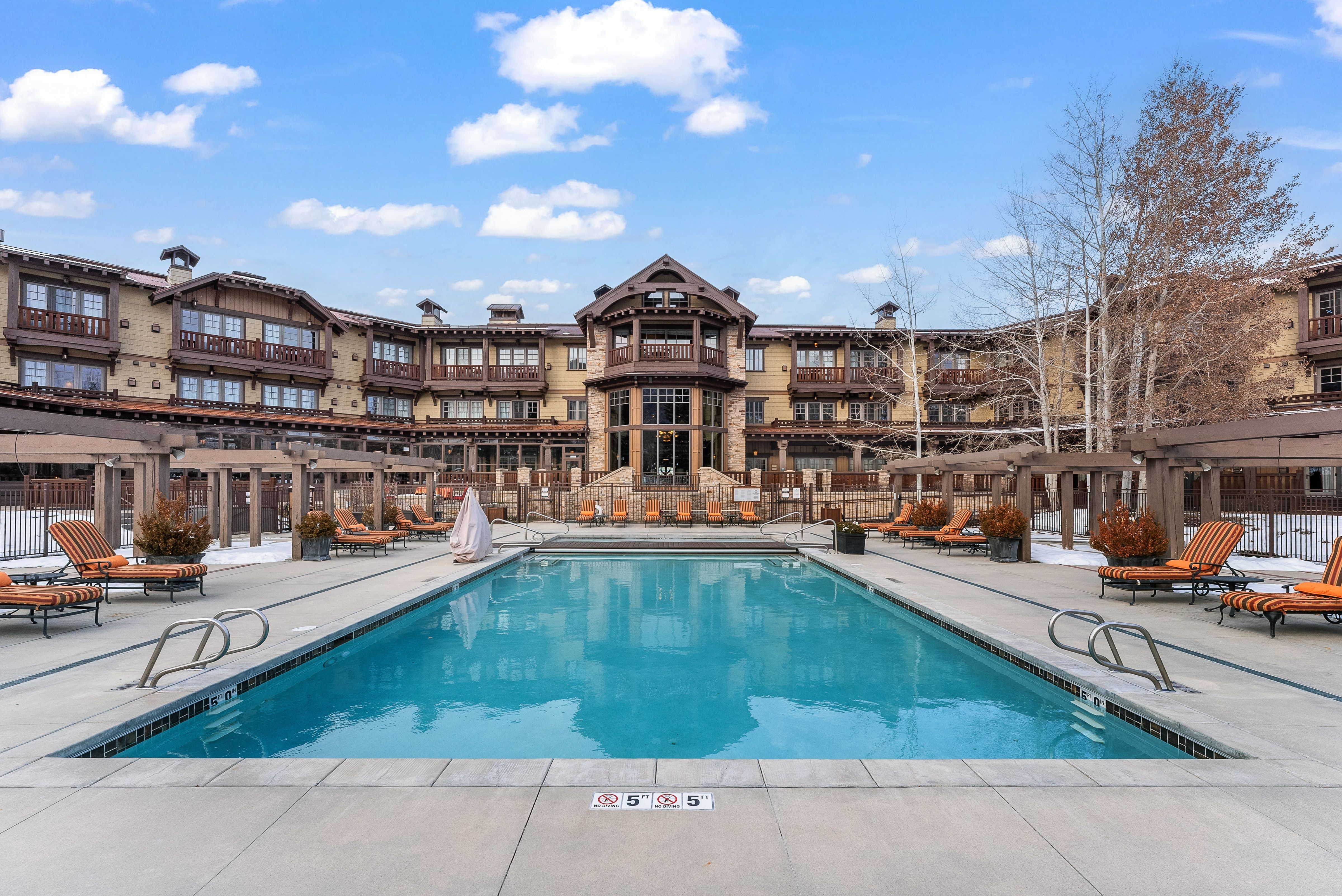 Outdoor swimming pool surrounded by a concrete deck with lounge seating