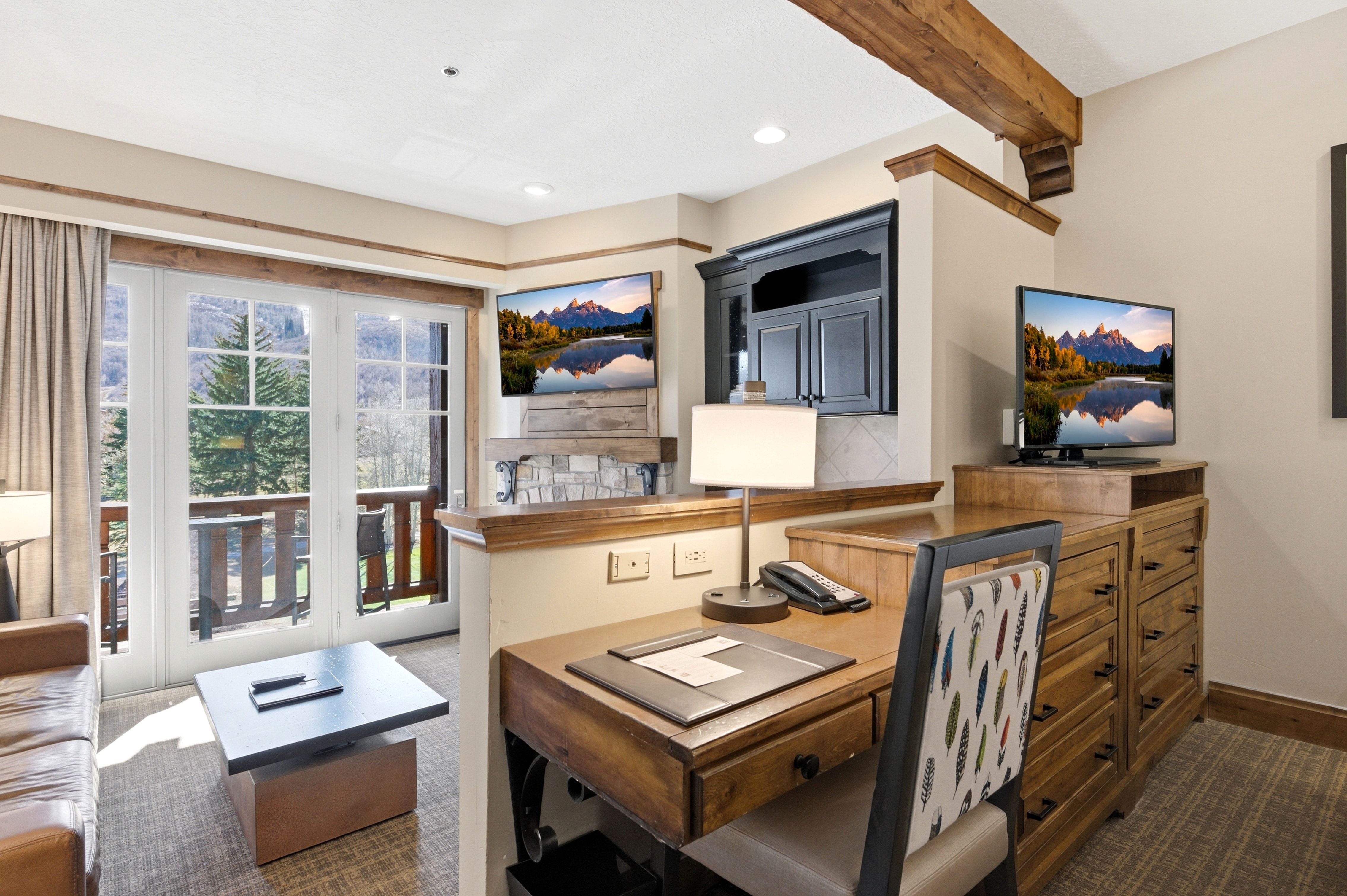Expansive French doors opening to an outdoor balcony, complemented by a wood beam ceiling