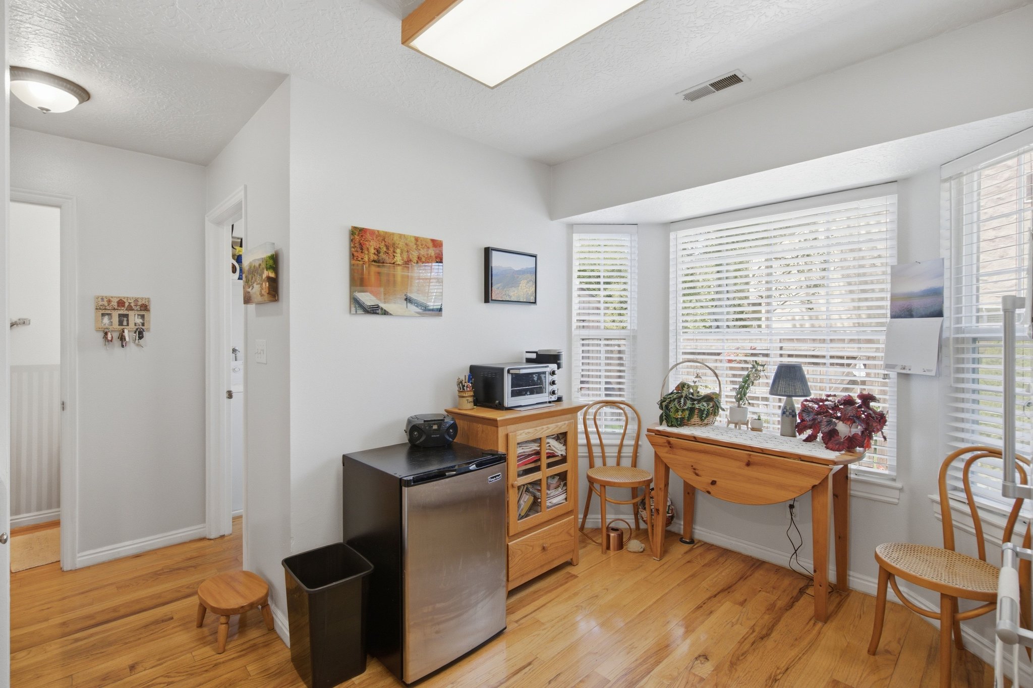 Bay window with white blinds, wood-finish flooring, and light neutral wall paint