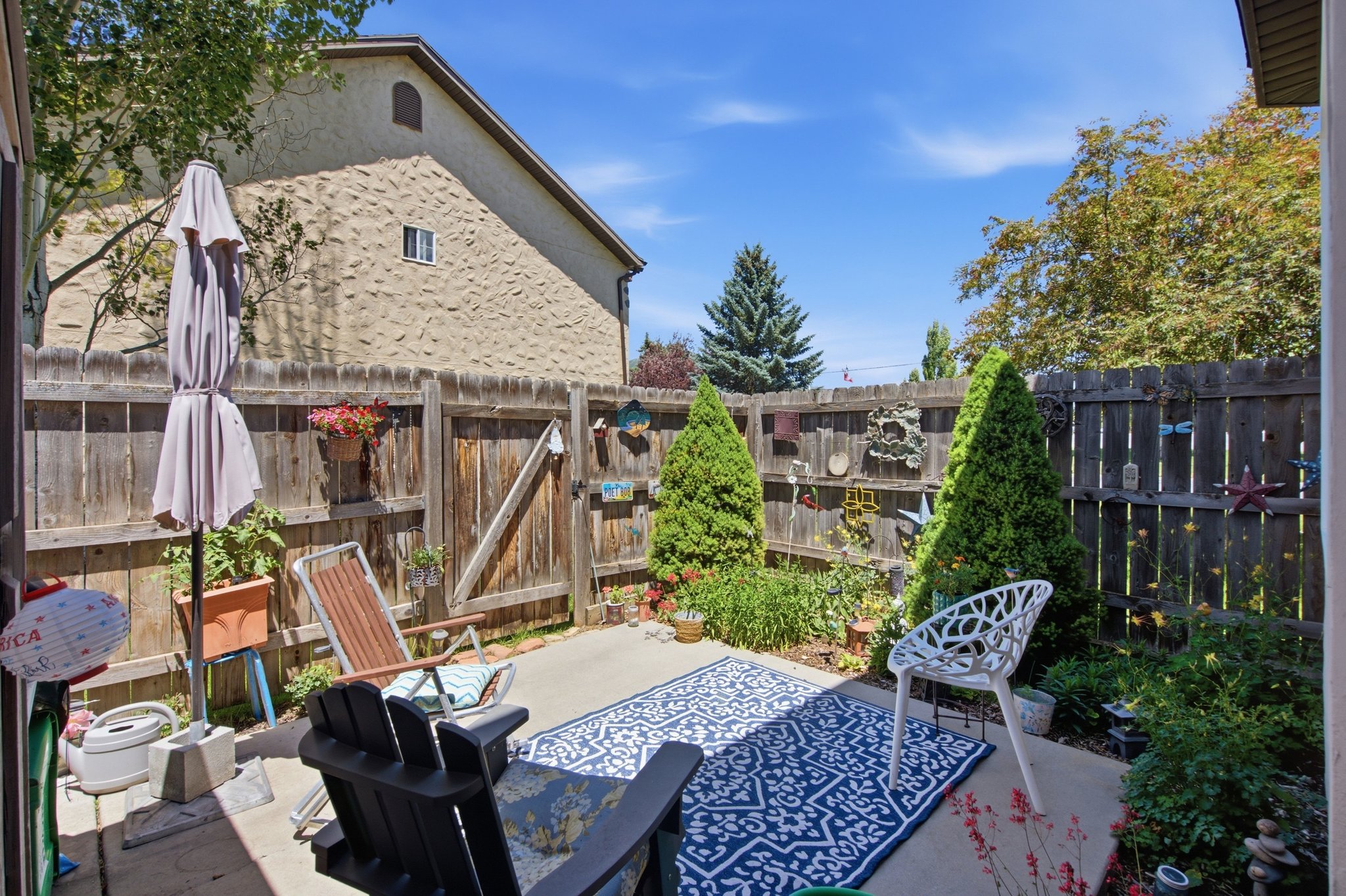Private patio space featuring a solid wood fence, established plantings, and concrete paving