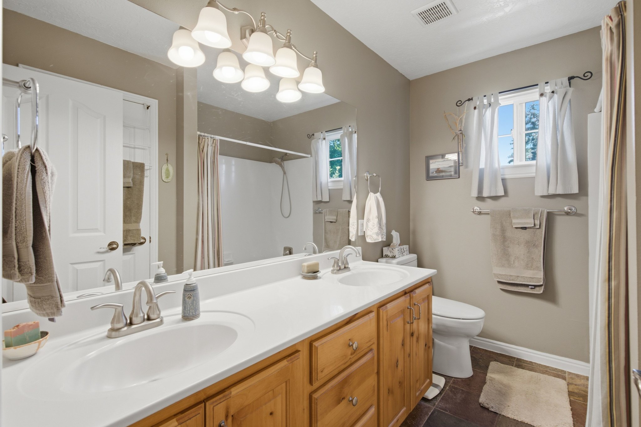 Double vanity with white integrated sinks, light wood-finish cabinetry, and brushed nickel fixtures