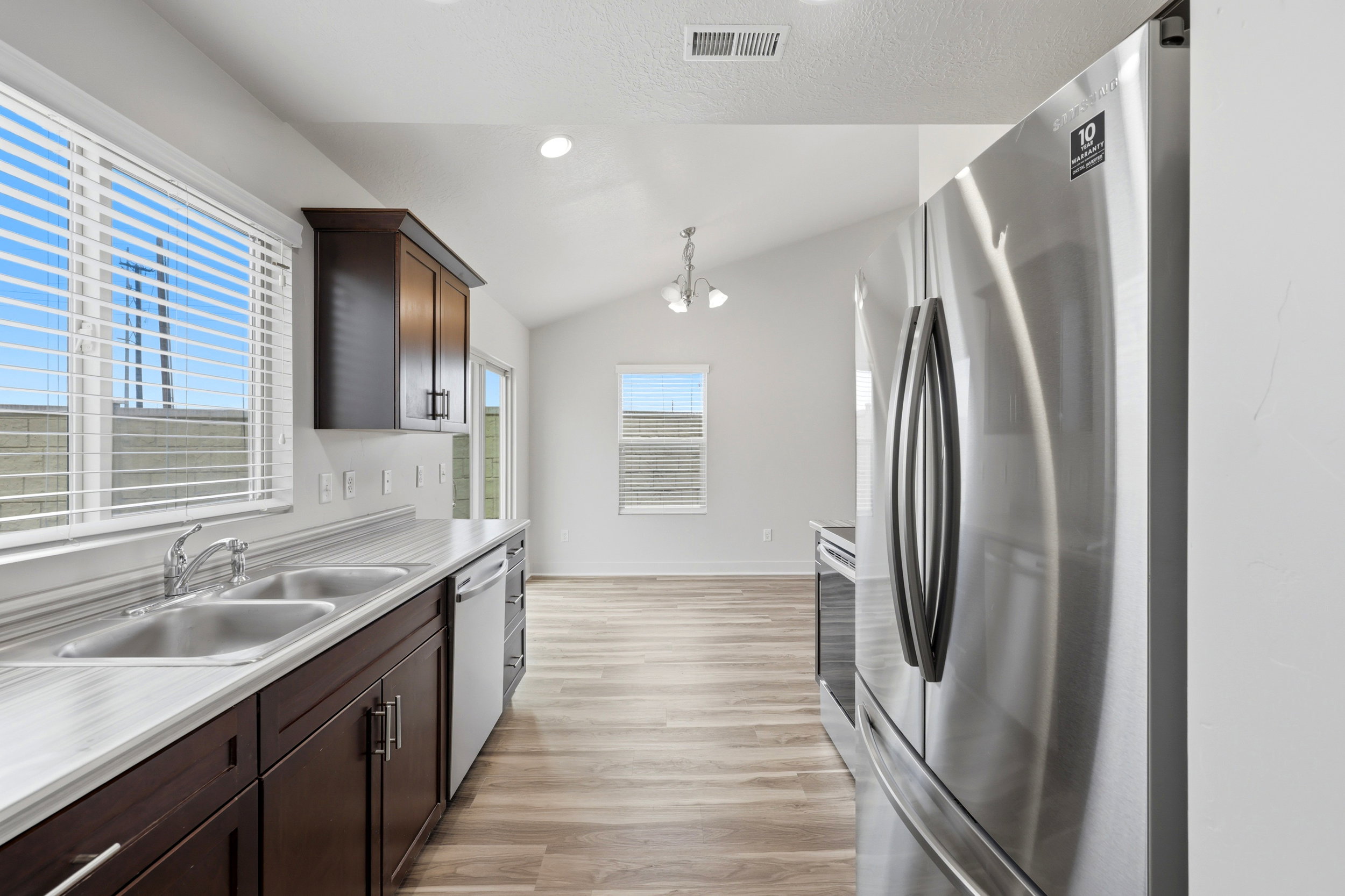 Kitchen featuring dark wood cabinetry, a double basin stainless steel sink, light-toned countertops, and stainless steel appliances