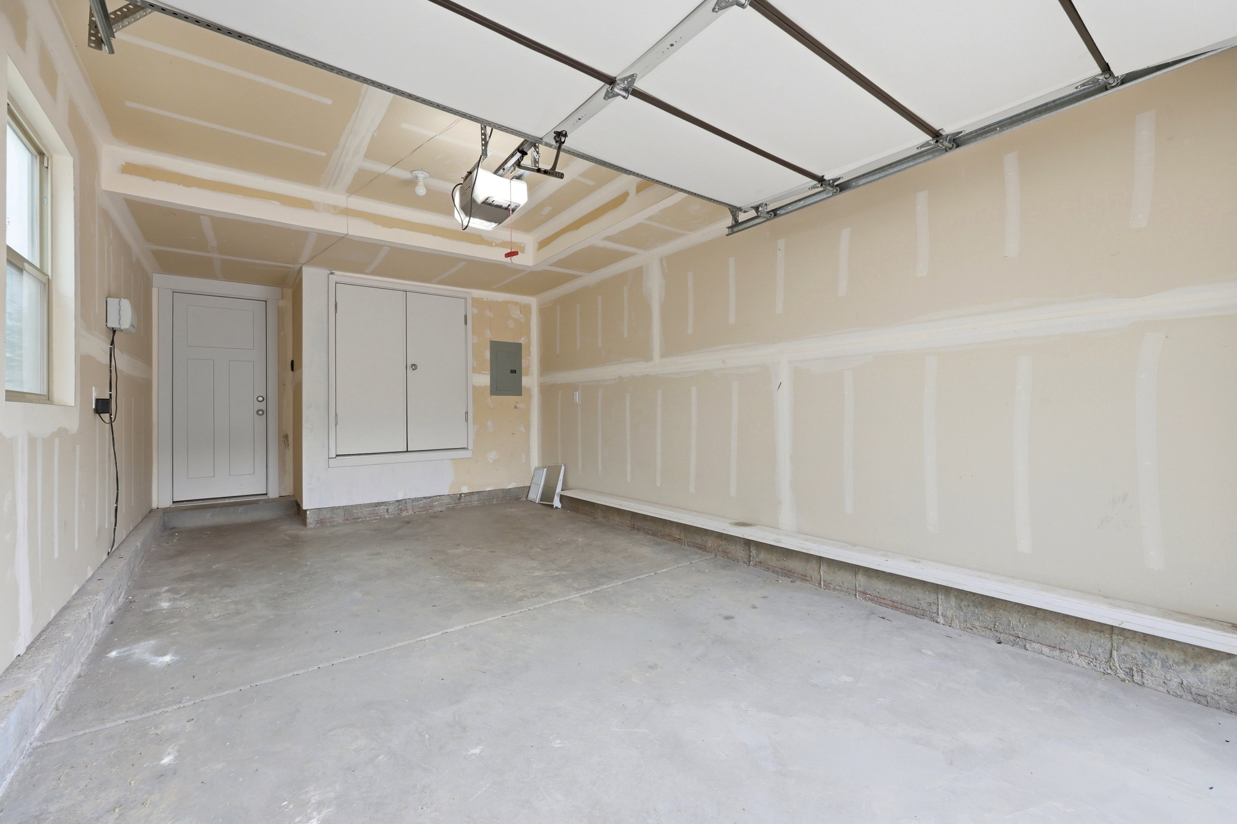 Spacious garage featuring a concrete floor, overhead door, automatic opener, a window, and an interior door