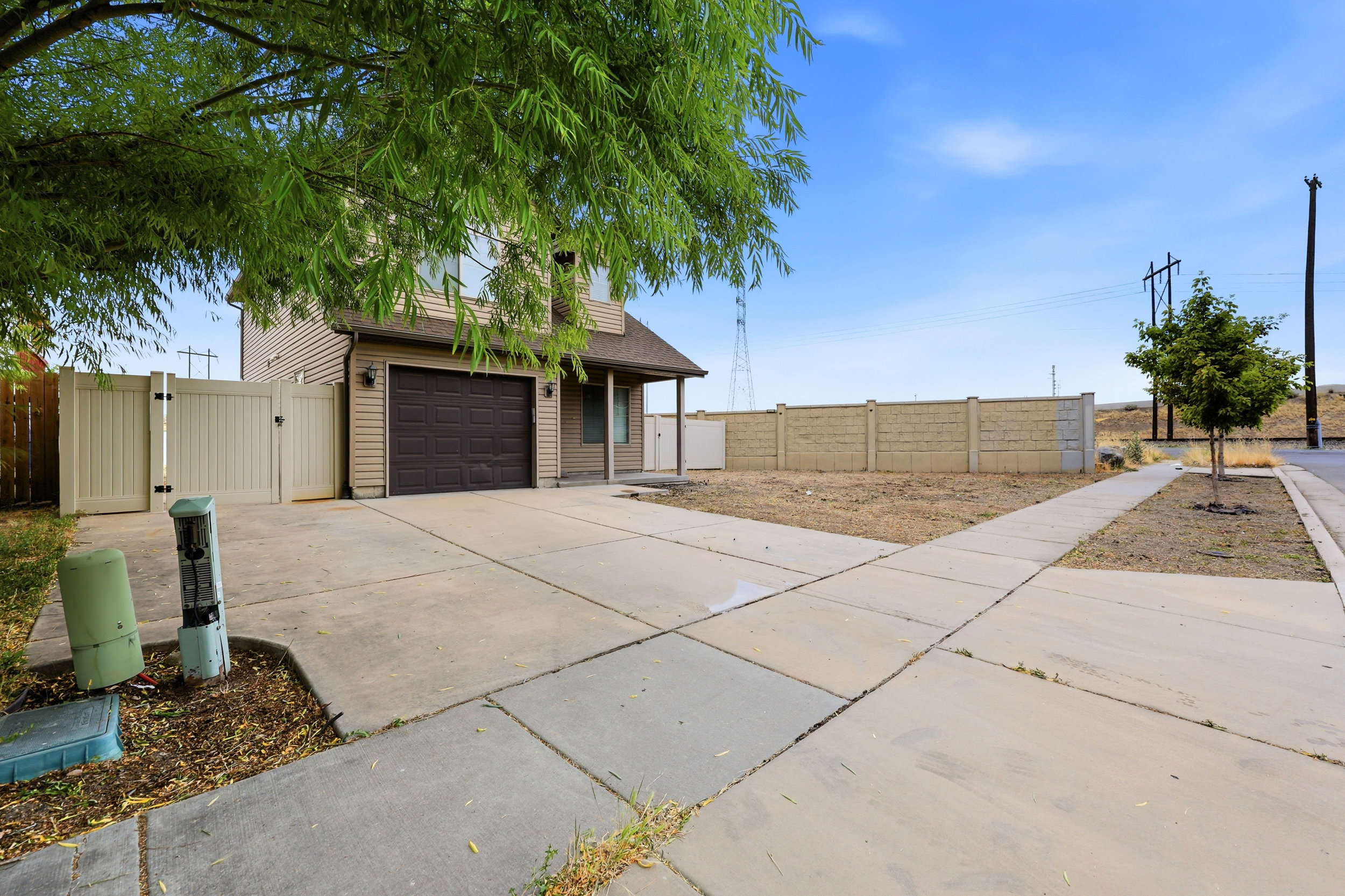 Two-story residence with light-toned siding, a dark garage door, and an extended driveway
