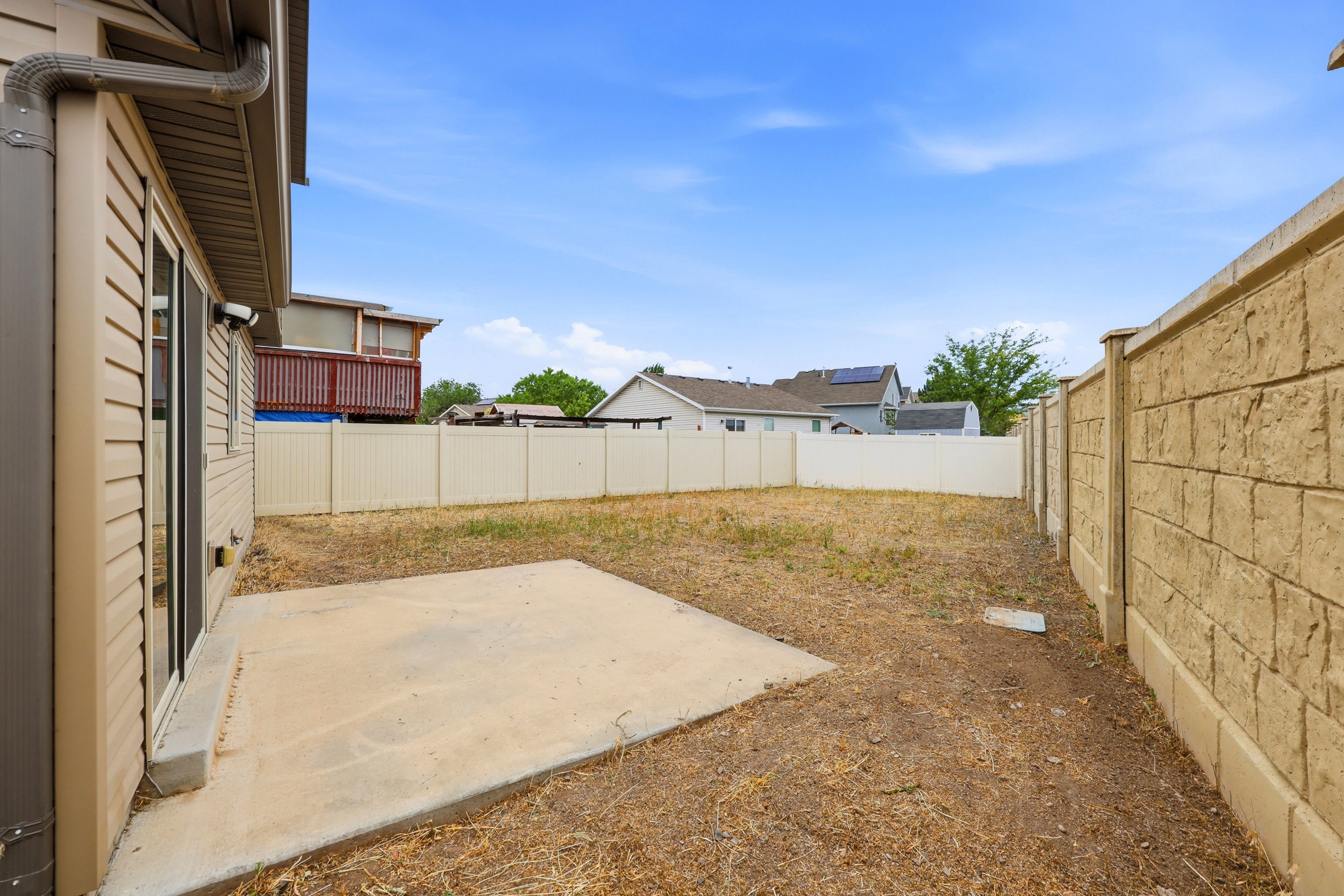 Spacious backyard featuring a concrete patio, vinyl siding, and a privacy fence