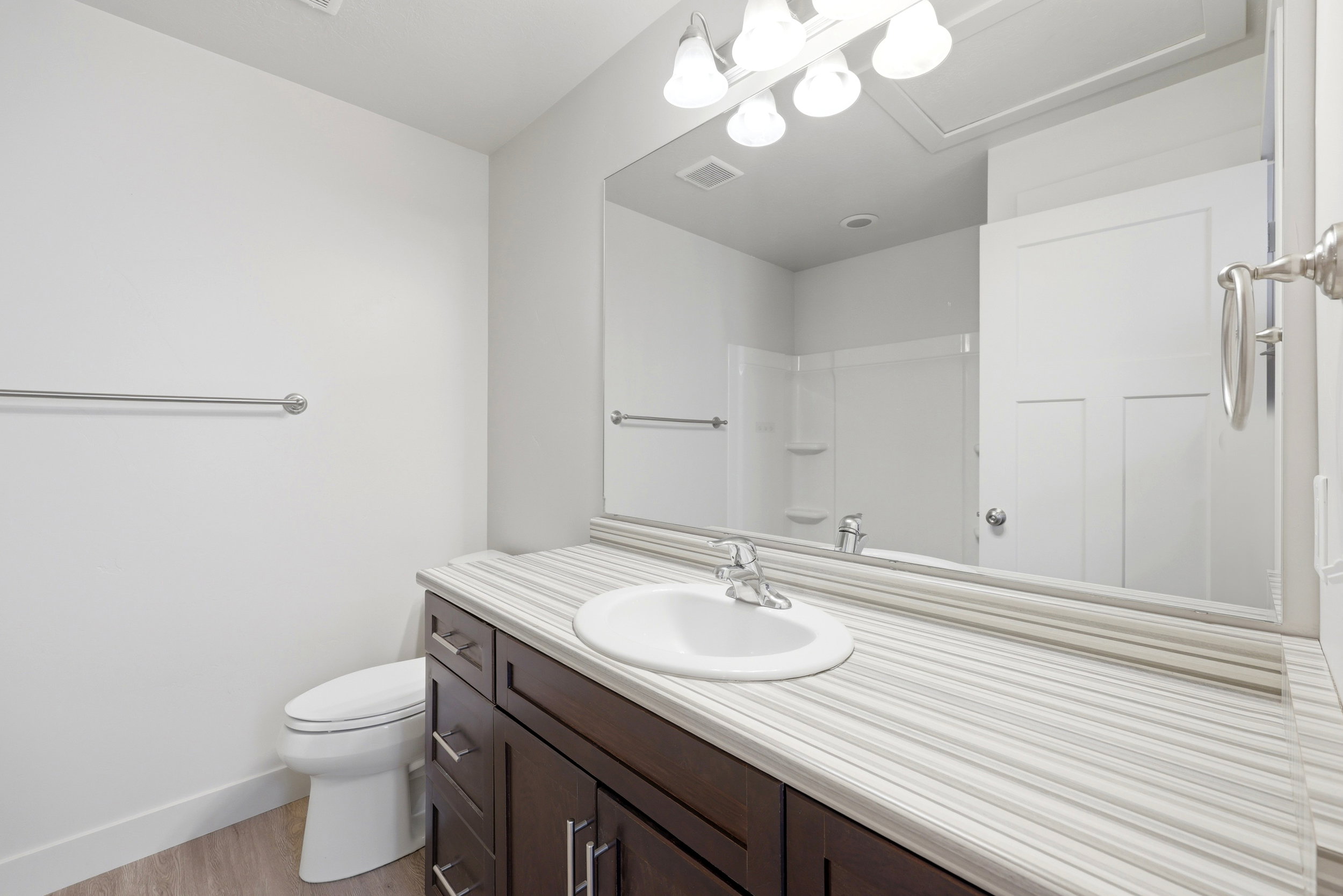 Bathroom featuring a dark wood-finish vanity with a white rectangular sink, a striped countertop, and a large wall-mounted mirror
