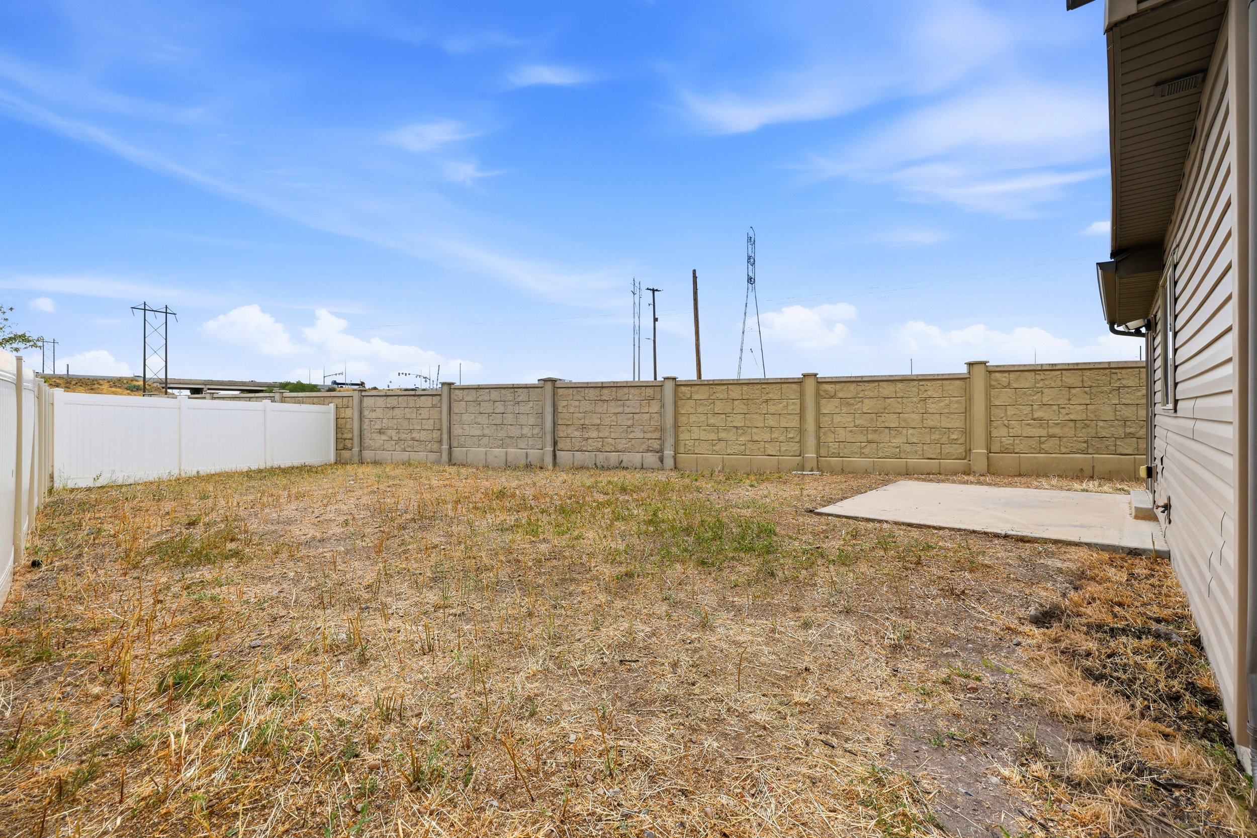 Fenced backyard featuring a concrete patio, vinyl siding exterior, and a combination of block and vinyl fencing