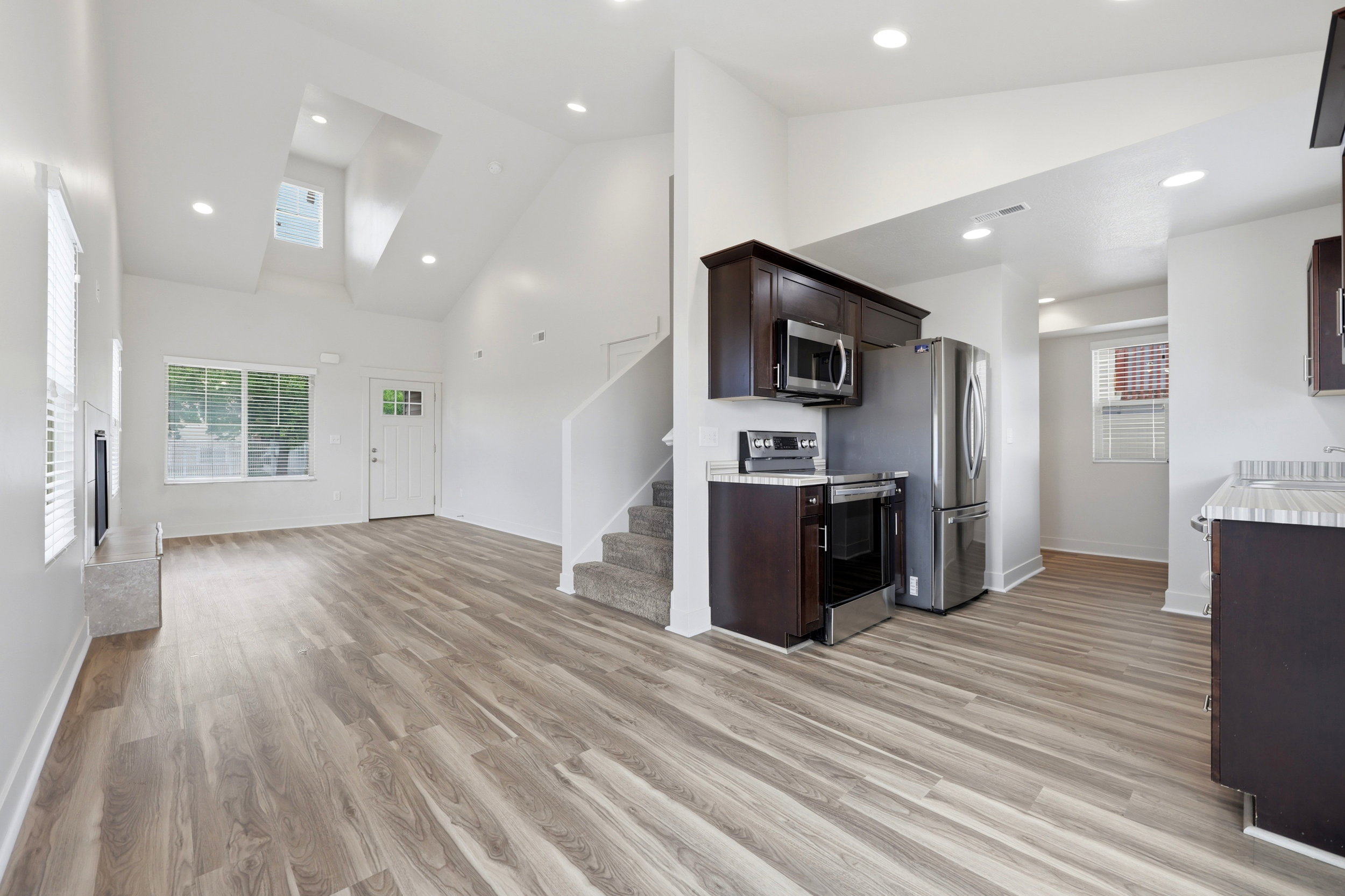 Open-concept interior featuring wood-finish flooring, vaulted ceilings, and recessed lighting
