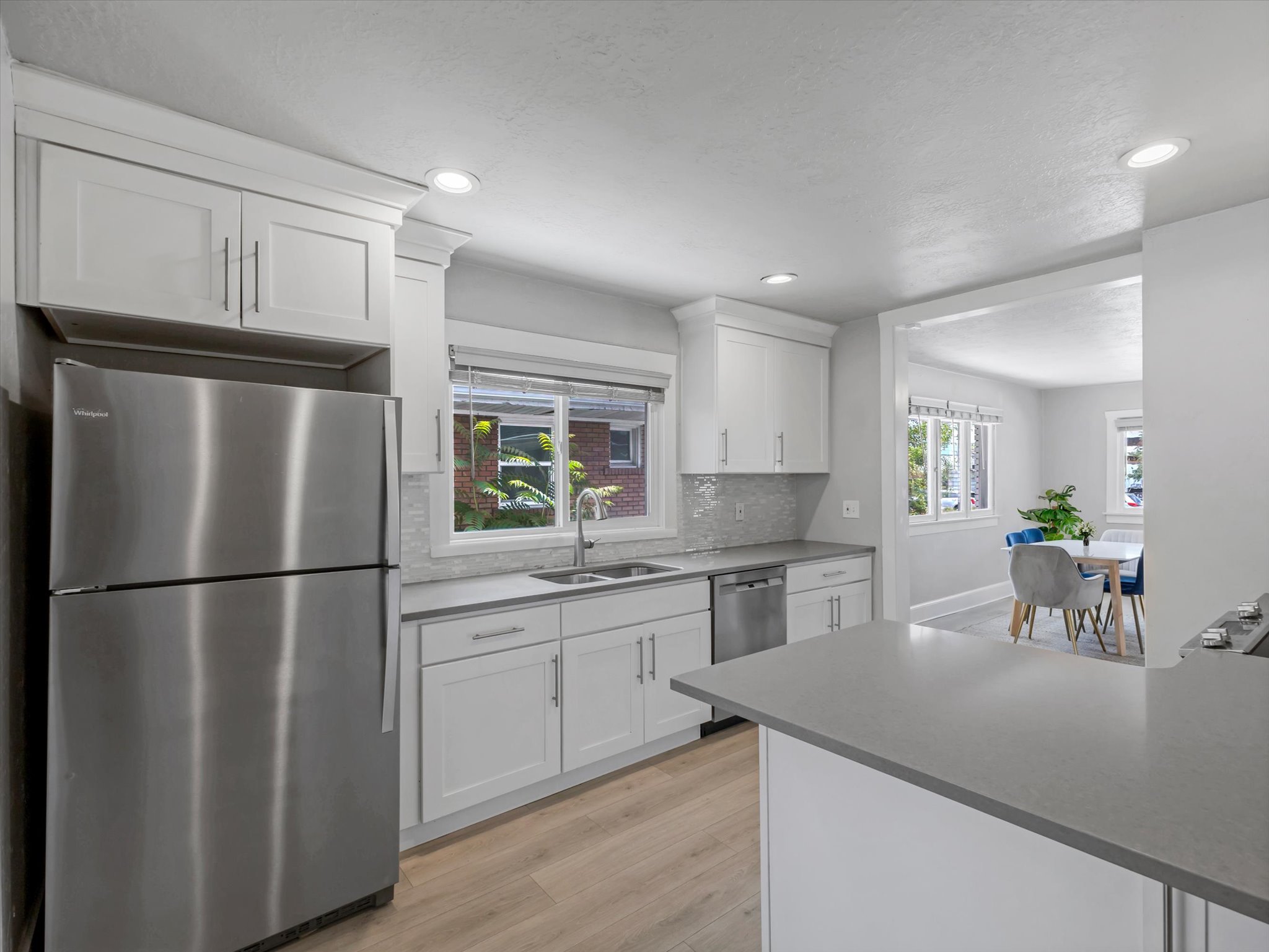 Modern kitchen featuring white shaker cabinetry, stainless steel appliances, and wood-finish flooring