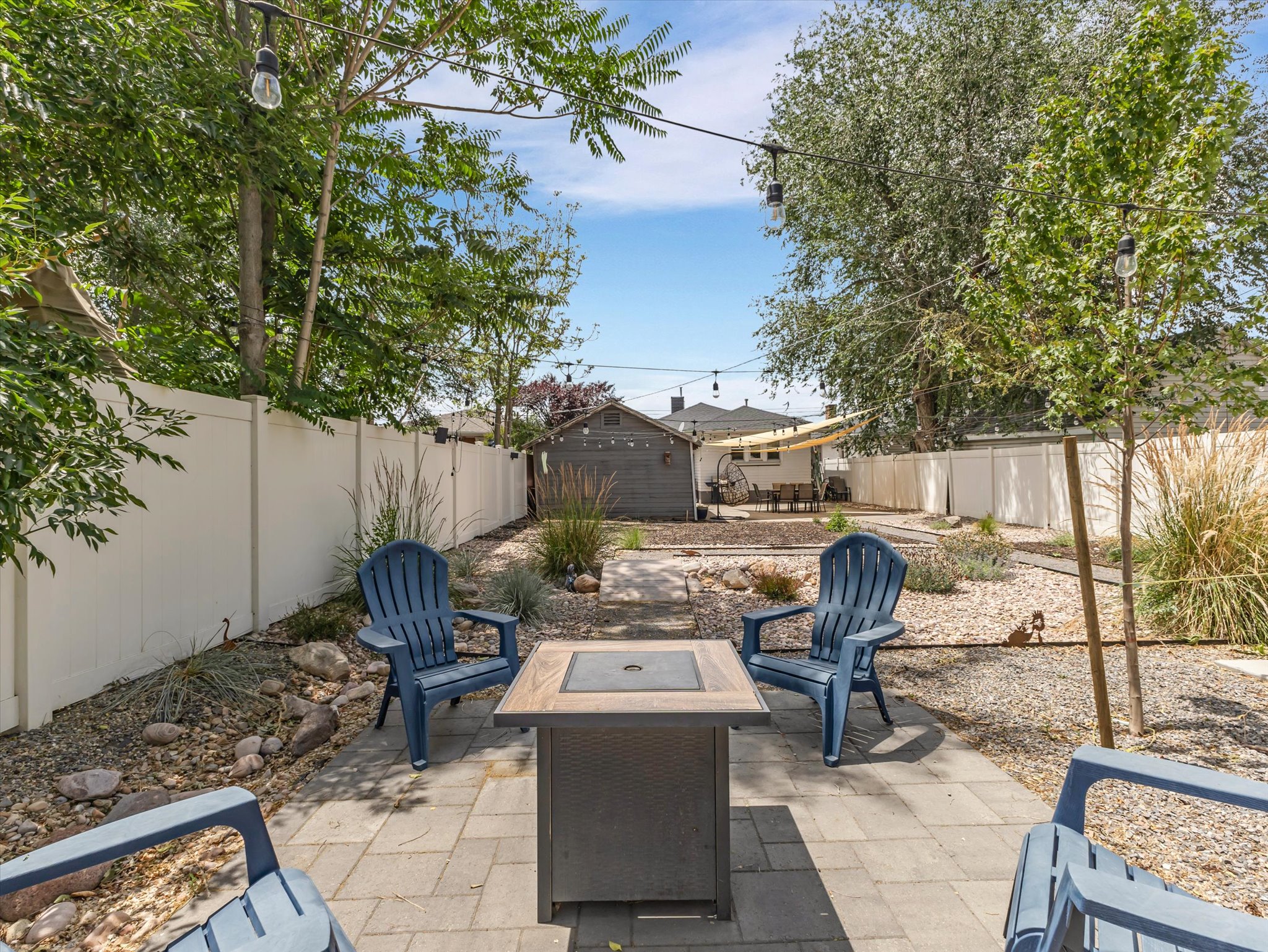 Patio area featuring paver flooring, a built-in fire pit, string lighting, and perimeter fencing