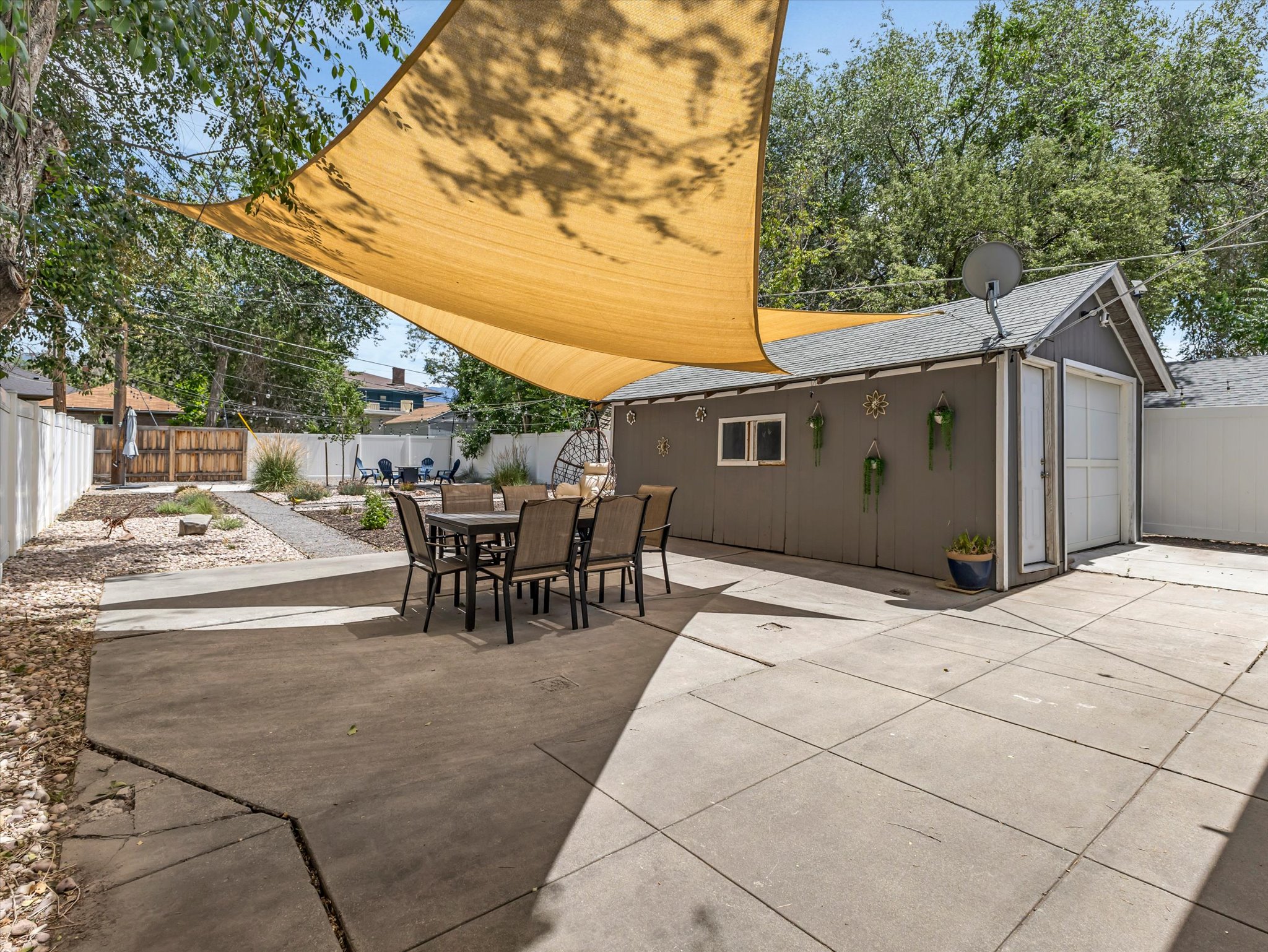 Backyard featuring concrete patio, shade sail, detached garage, and perimeter fencing