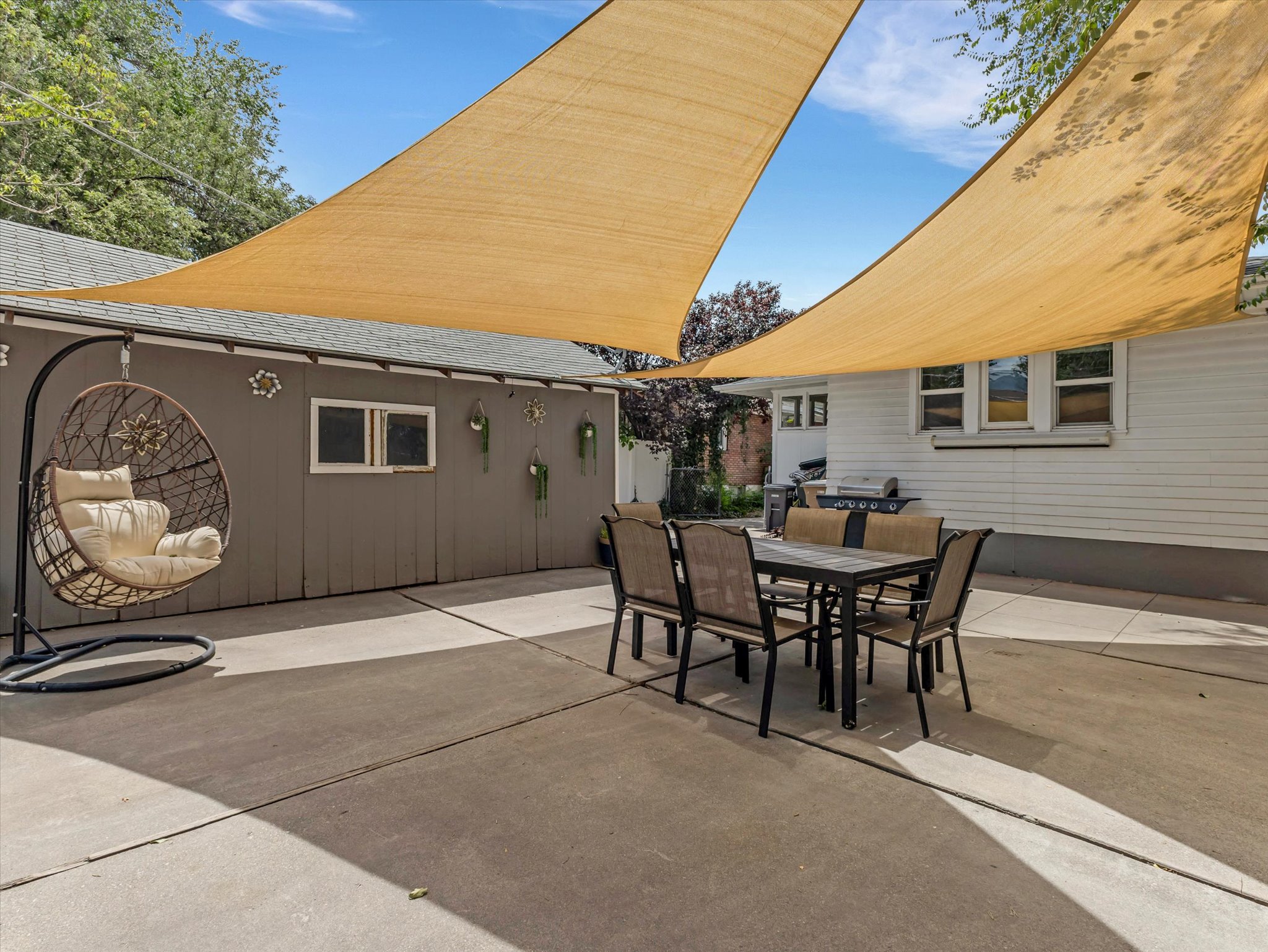 Expansive concrete patio area with two large overhead shade sails
