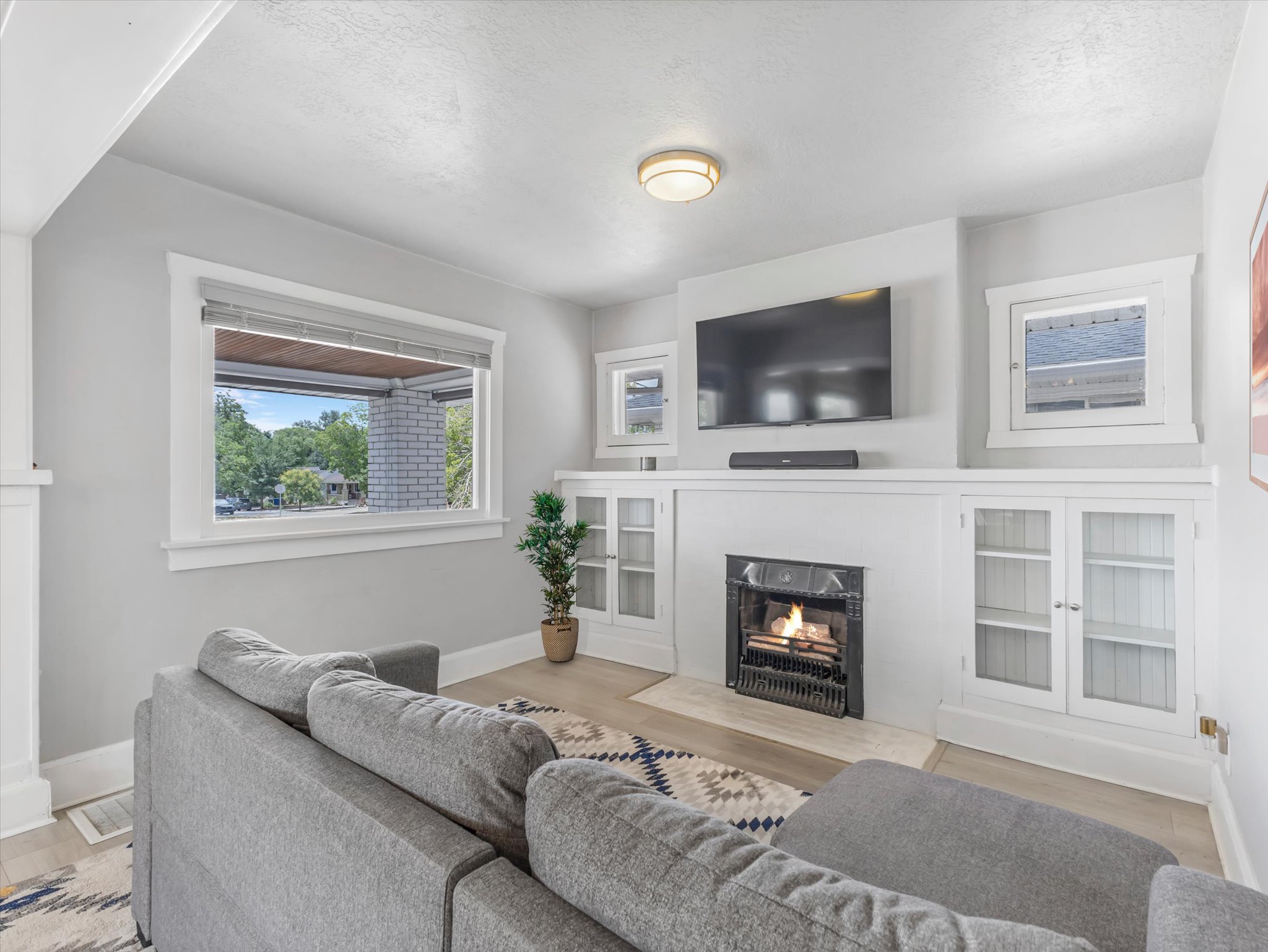 Living area featuring a central fireplace with an ornate black insert, flanked by built-in cabinetry with glass panel doors