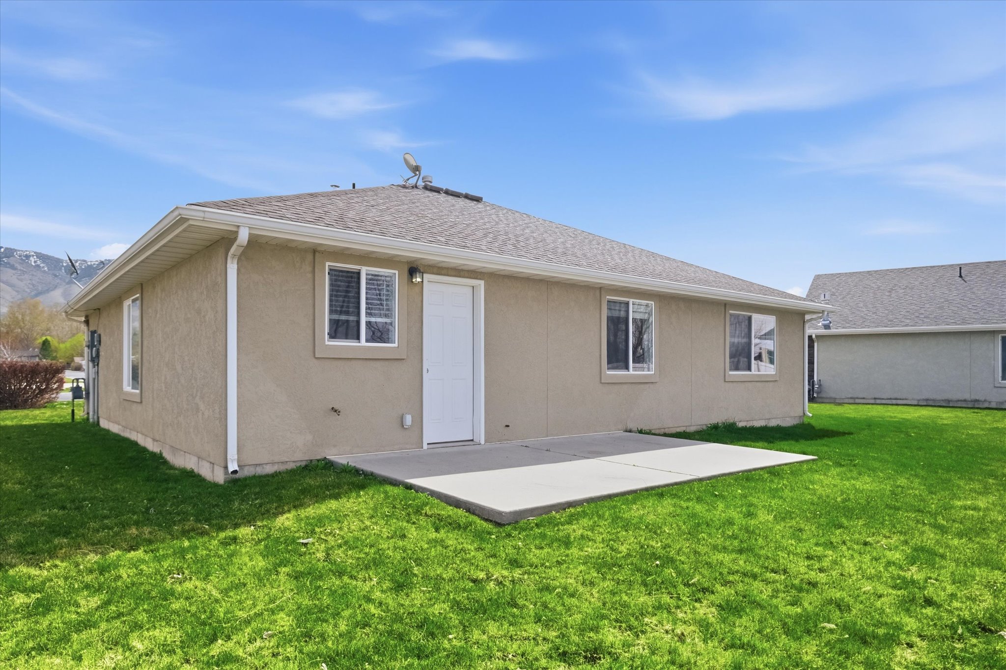 Expansive grass lawn surrounding the stucco exterior
