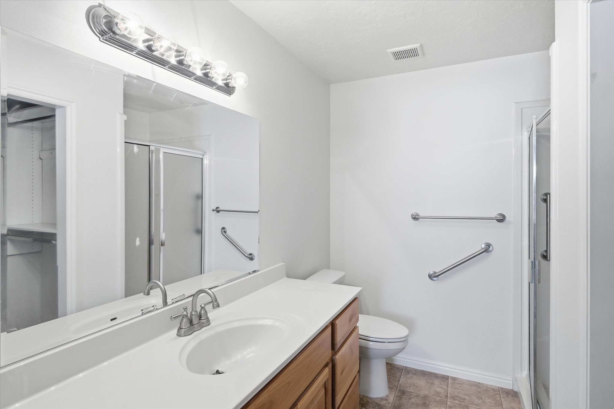 Bathroom featuring a single vanity with wood cabinetry, a white countertop, and an integrated sink