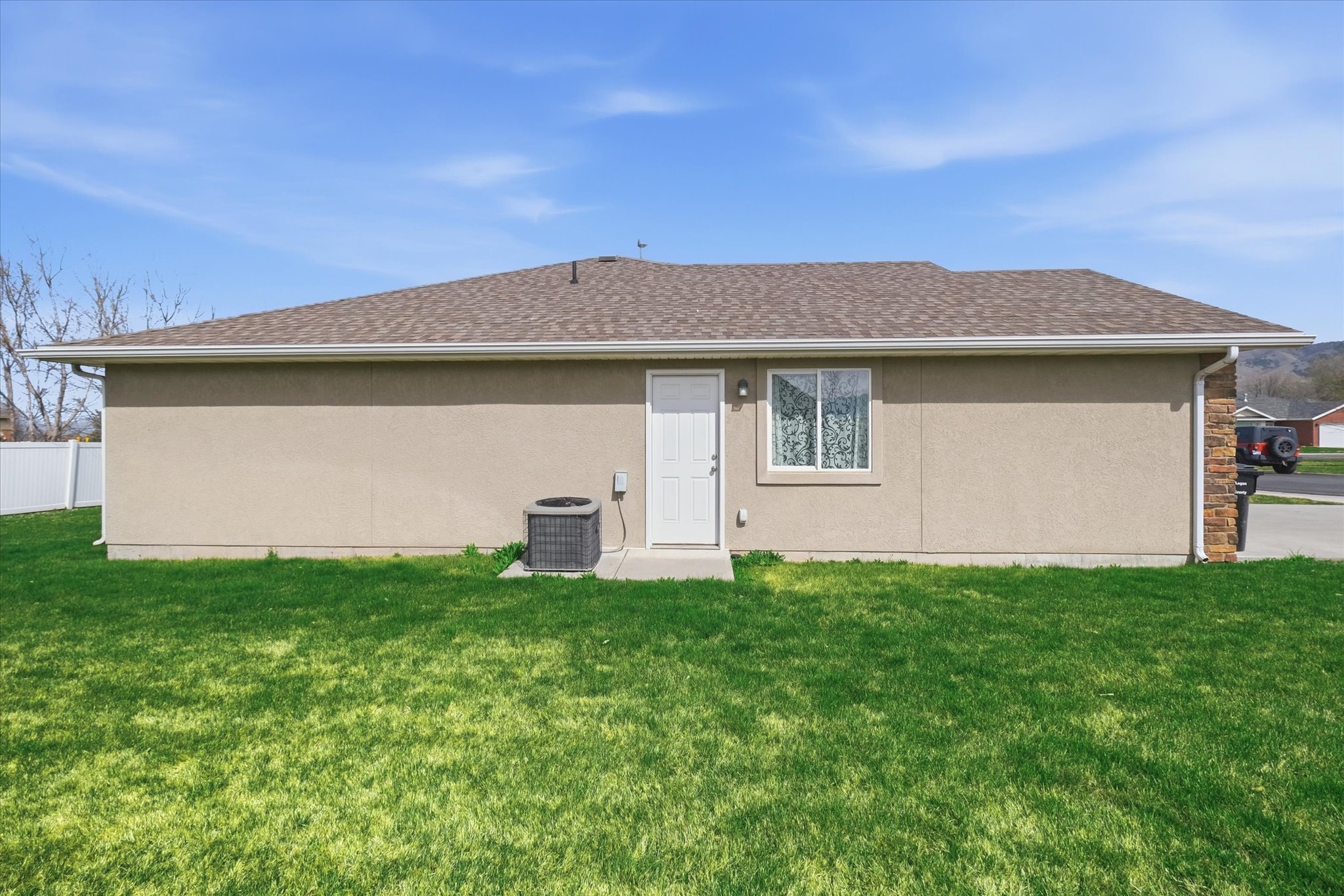 Stucco exterior featuring a brown shingle roof, white trim, and a white entry door