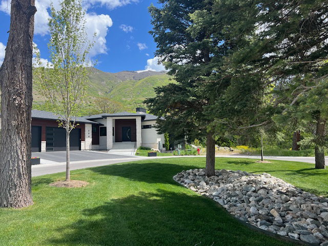 Contemporary architectural design featuring a prominent entryway, a multi-car garage, and a manicured lawn