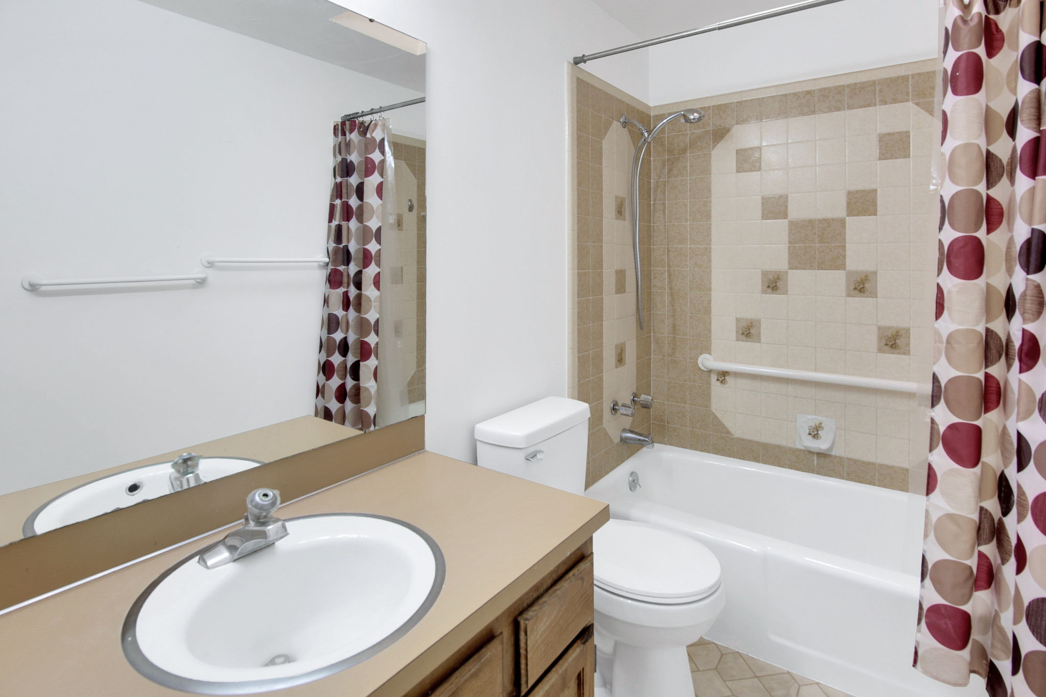 Bathroom featuring a built-in tub with tile surround, a single vanity with an integrated sink, and a wall-mounted mirror