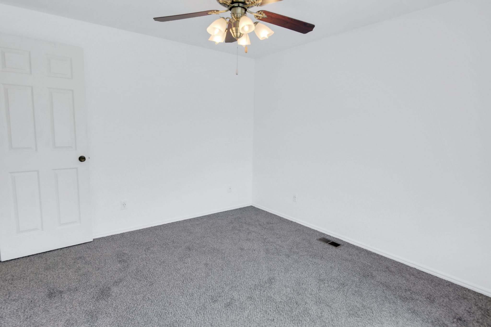 Room featuring a ceiling fan with light fixture, neutral carpet flooring, and a six-panel interior door
