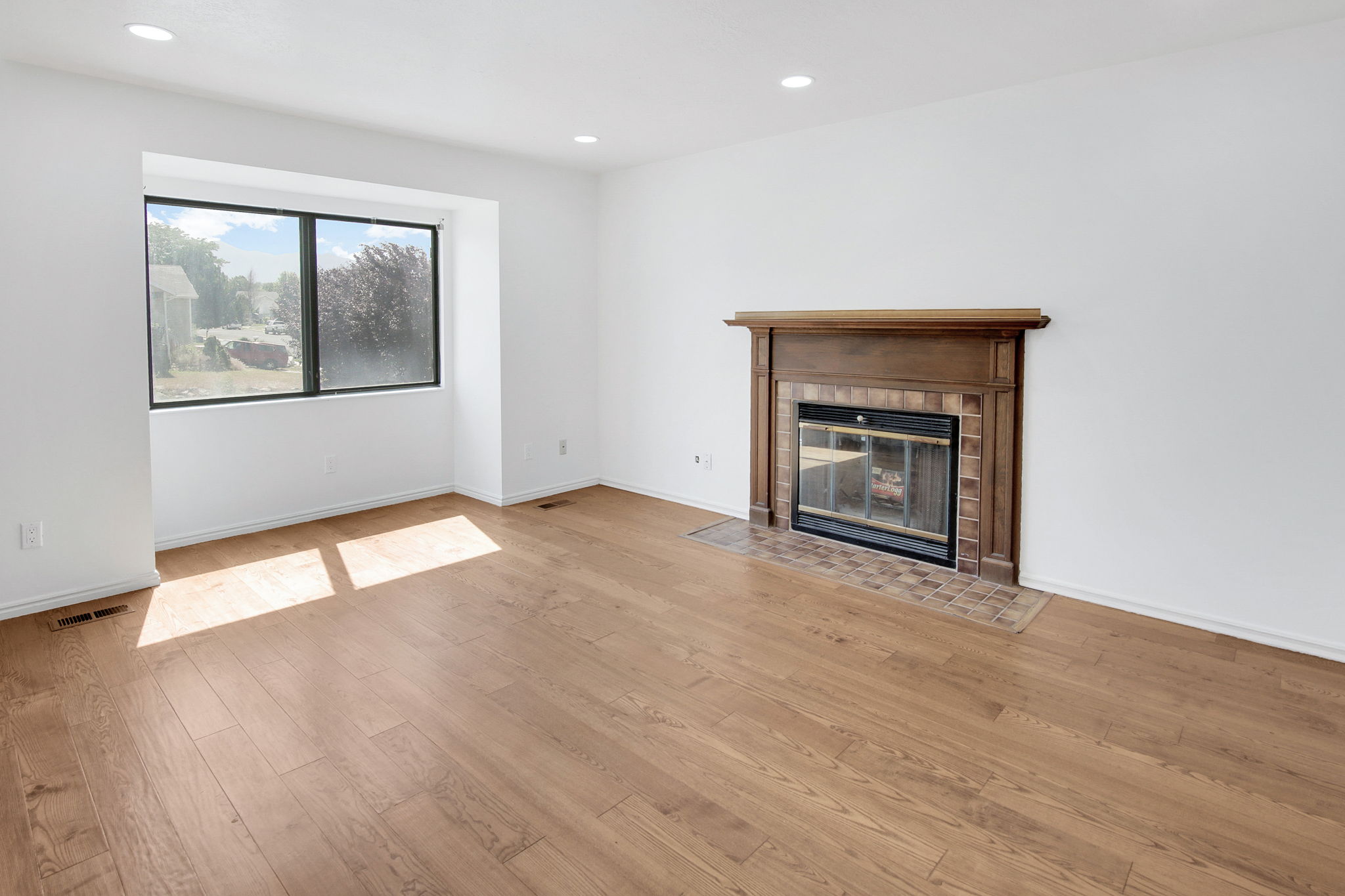 Living area featuring wood-finish flooring and a fireplace with a wood mantle