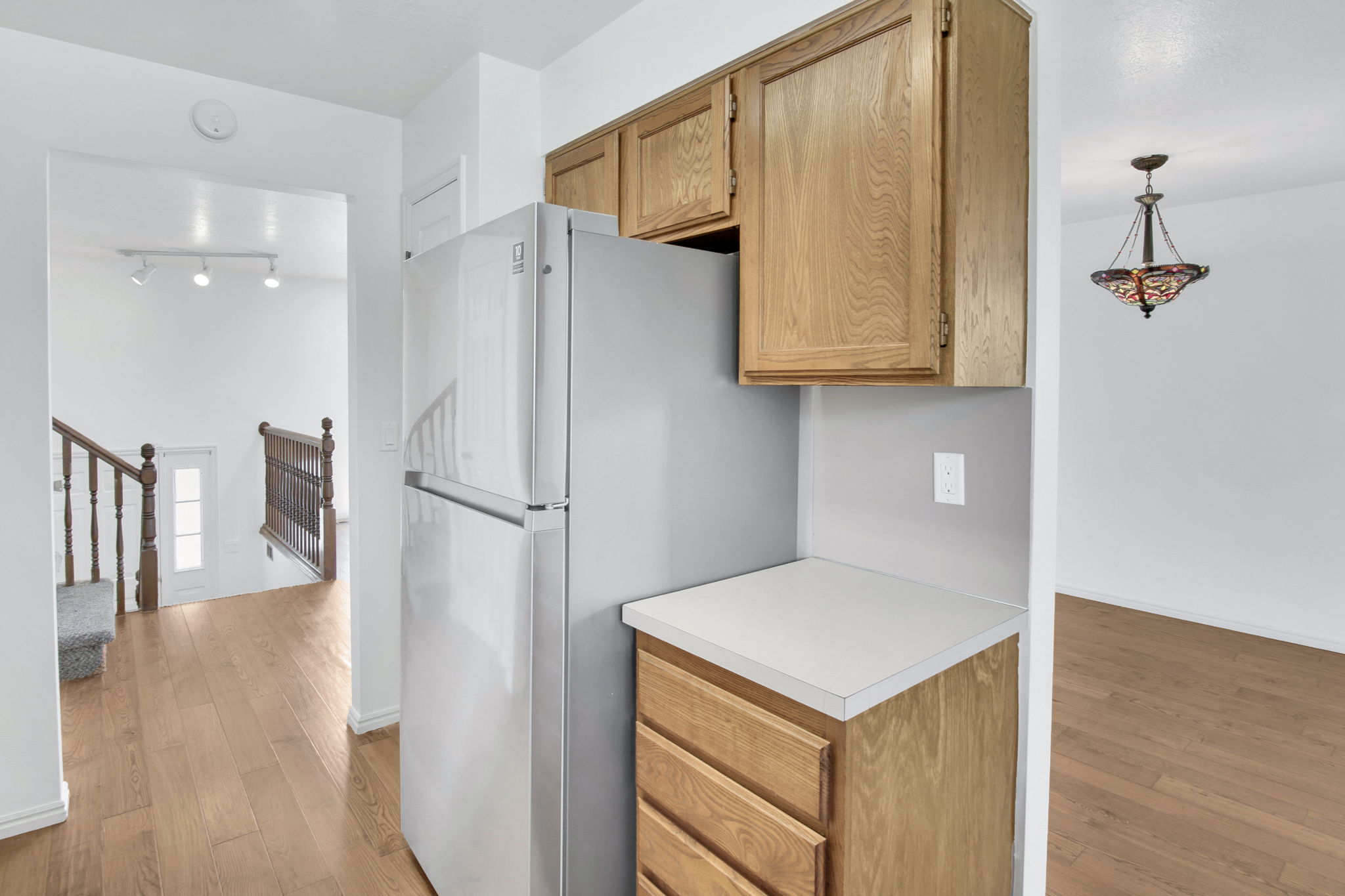 Kitchenette area featuring wood-finish cabinetry, a light-toned countertop, and a stainless steel-finish refrigerator