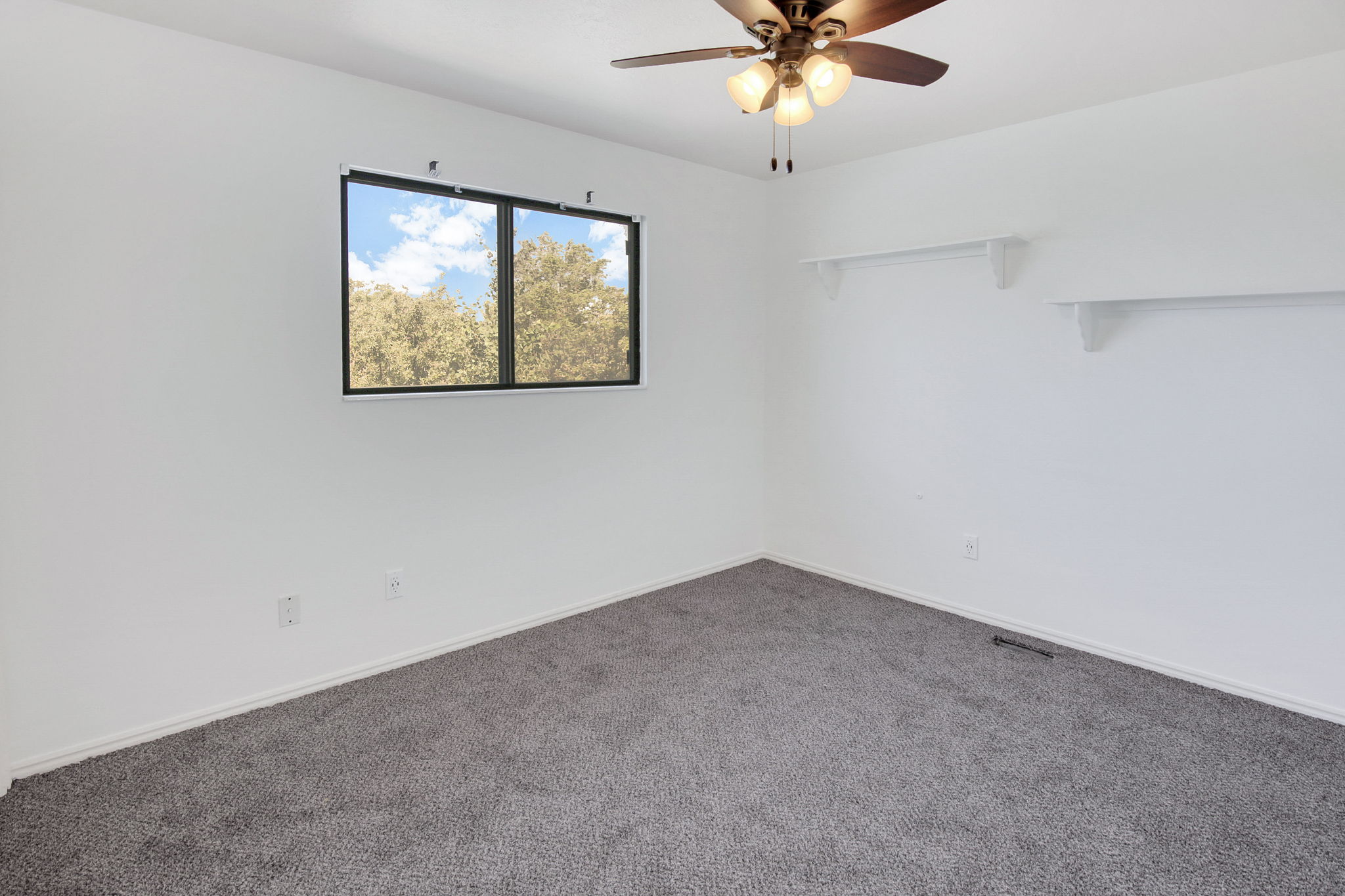 Interior space featuring gray carpeting, white walls, a dual-pane window, and a ceiling fan with light fixture