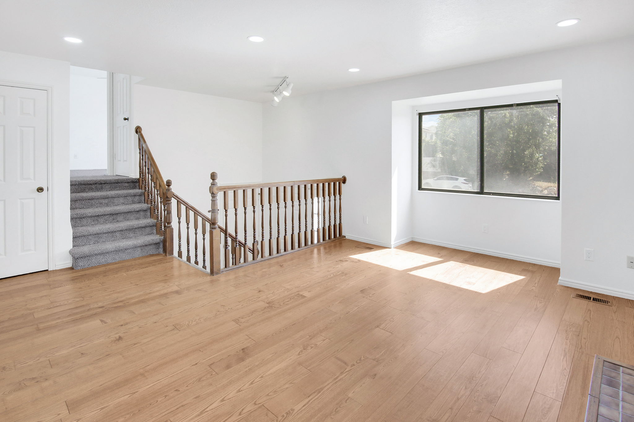 Open-concept living area featuring wood-finish flooring, a large picture window, and recessed lighting