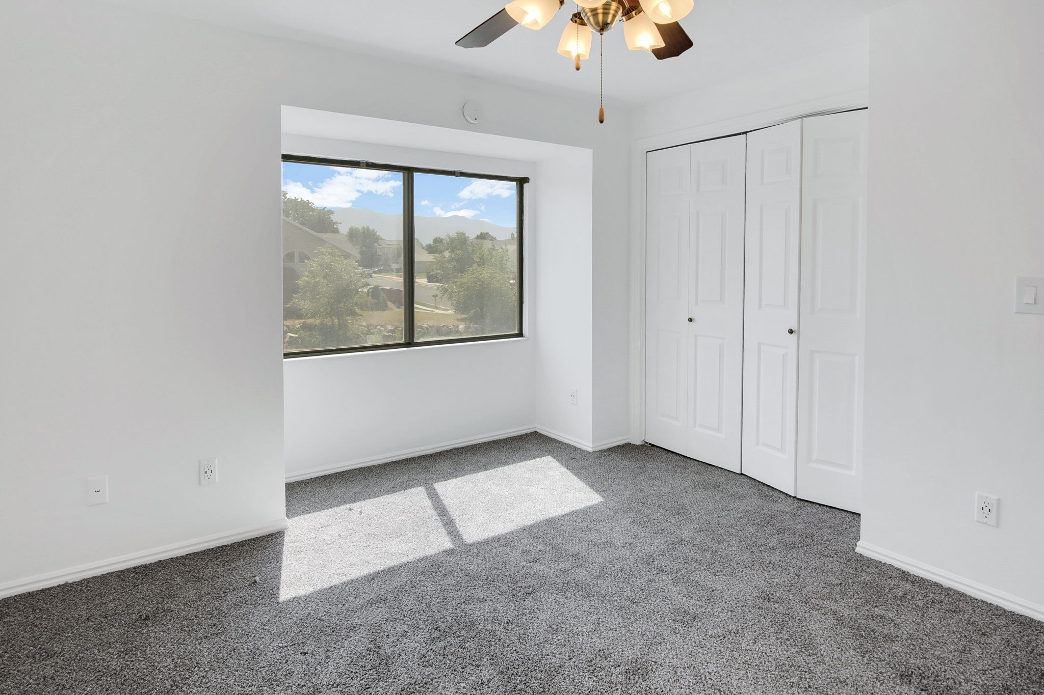 Room featuring neutral-toned carpet flooring, white walls, and a large window