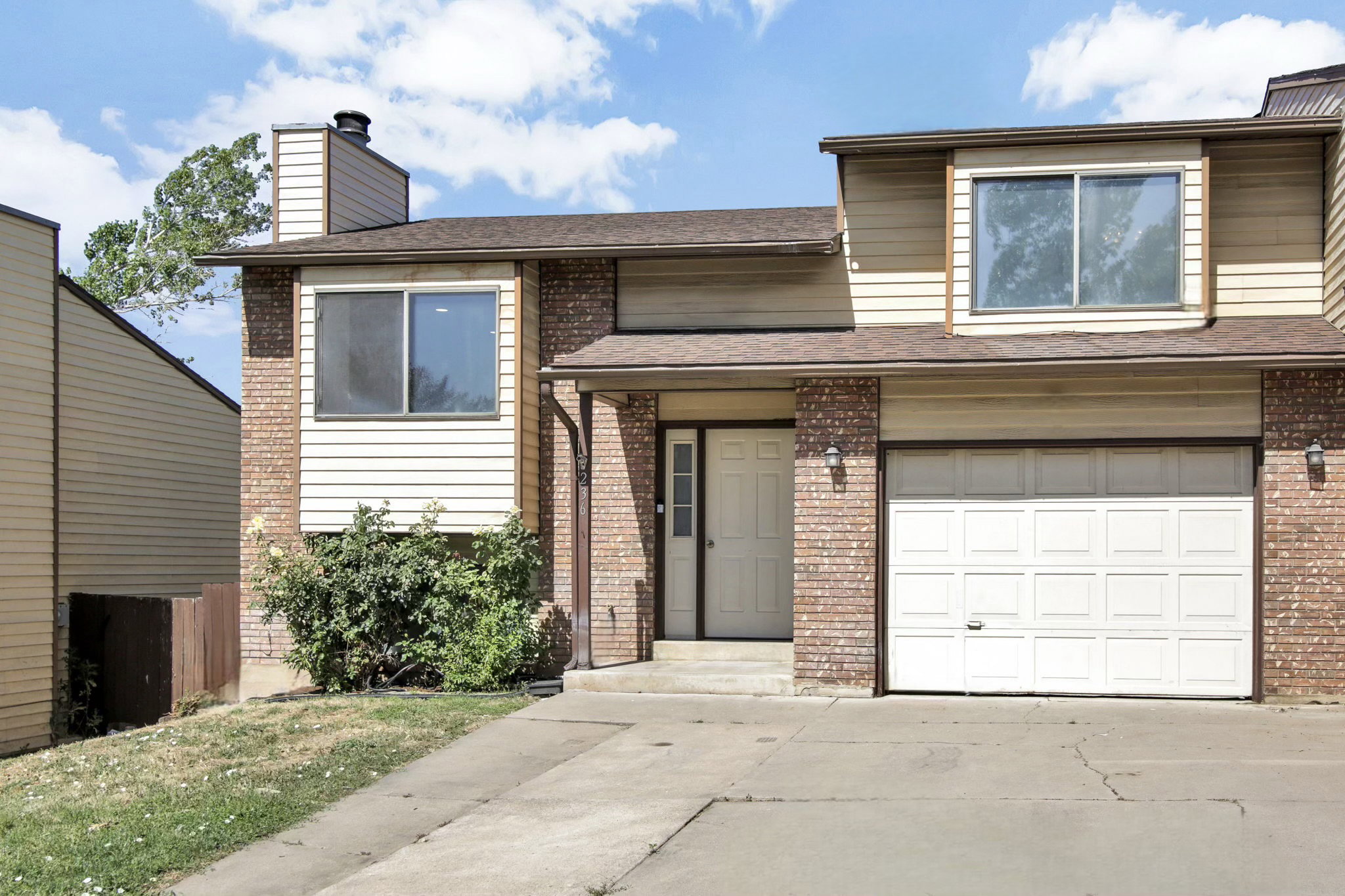 Brick and siding exterior featuring an attached garage, covered entryway, and second-story window dormer