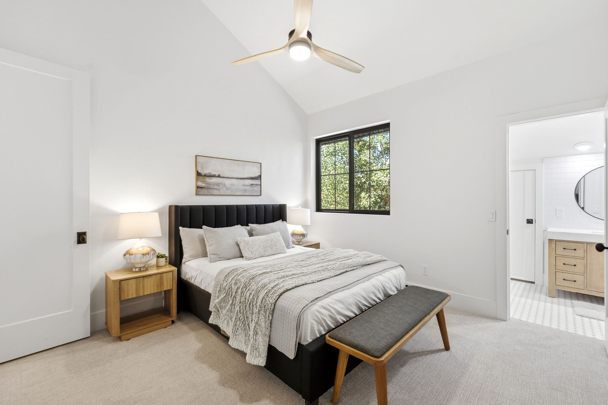 Vaulted ceiling bedroom featuring a modern ceiling fan, large window with black trim, and light-toned carpeting