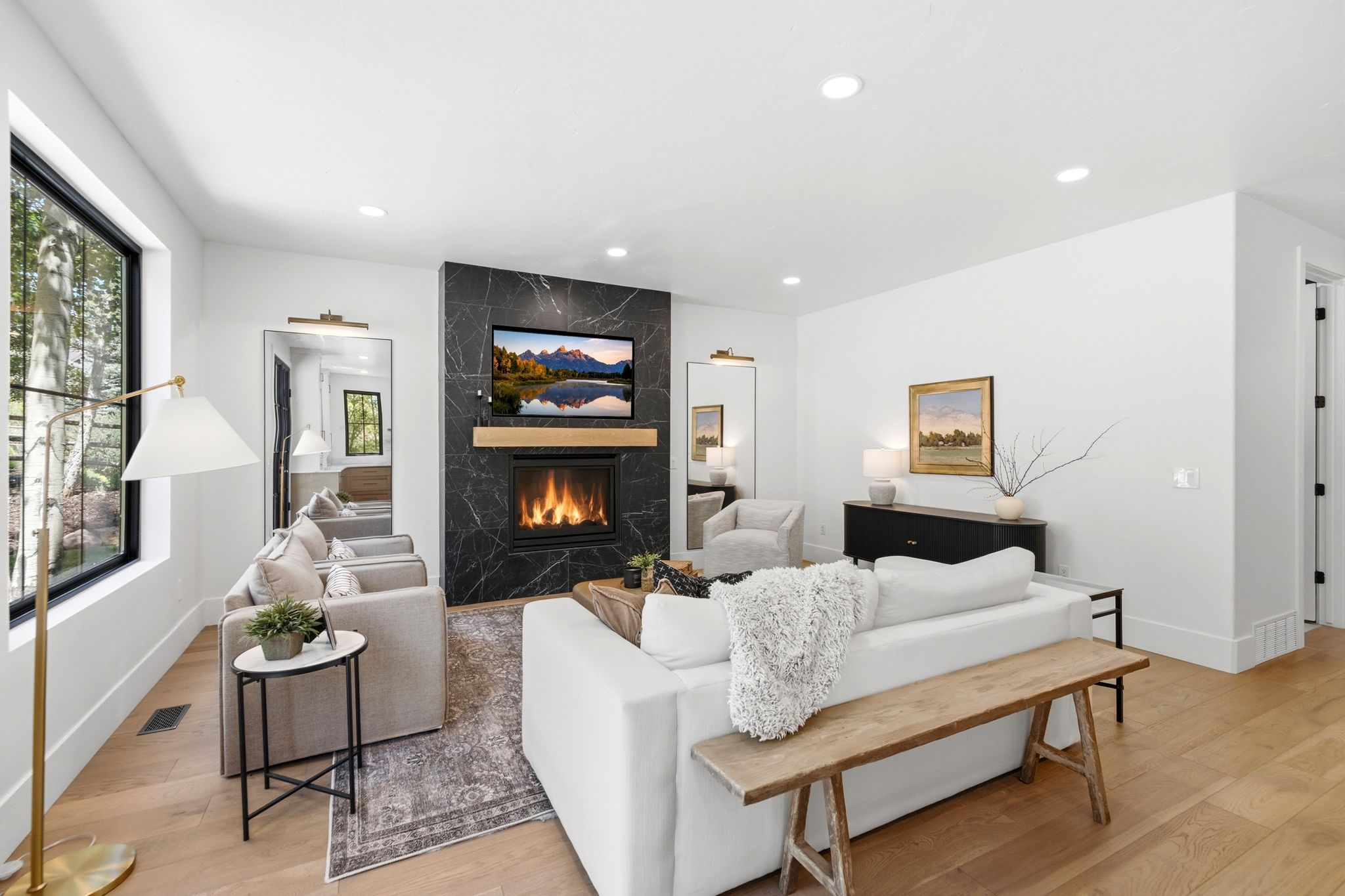 Spacious room featuring light wood-finish flooring, recessed lighting, and a modern fireplace with a dark stone surround and wood mantel