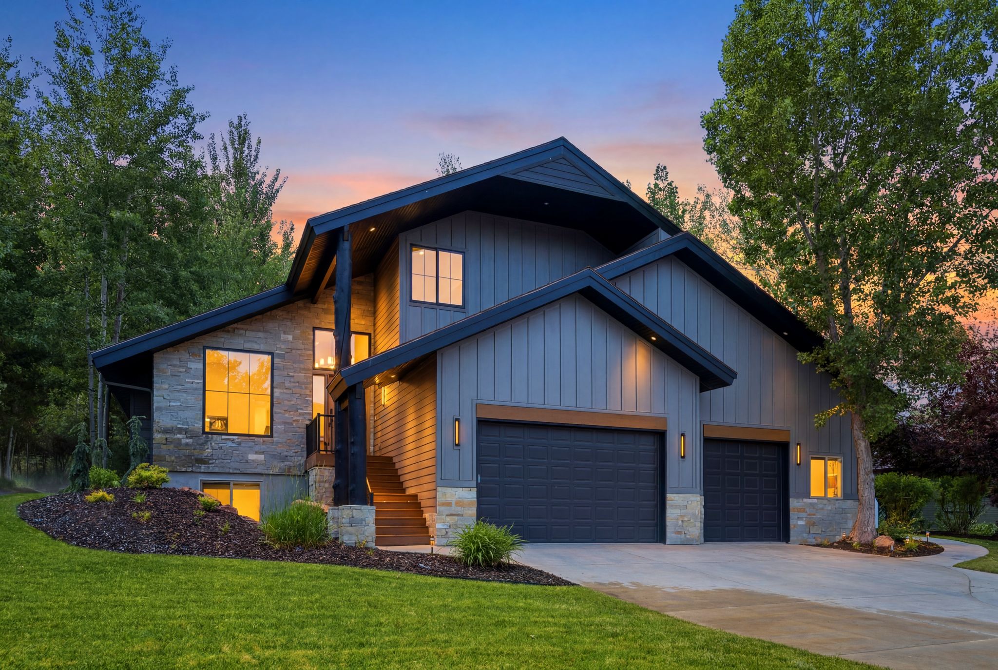 Contemporary exterior featuring board and batten siding, stone accents, multiple large windows, a multi-level entryway, and a two-car garage