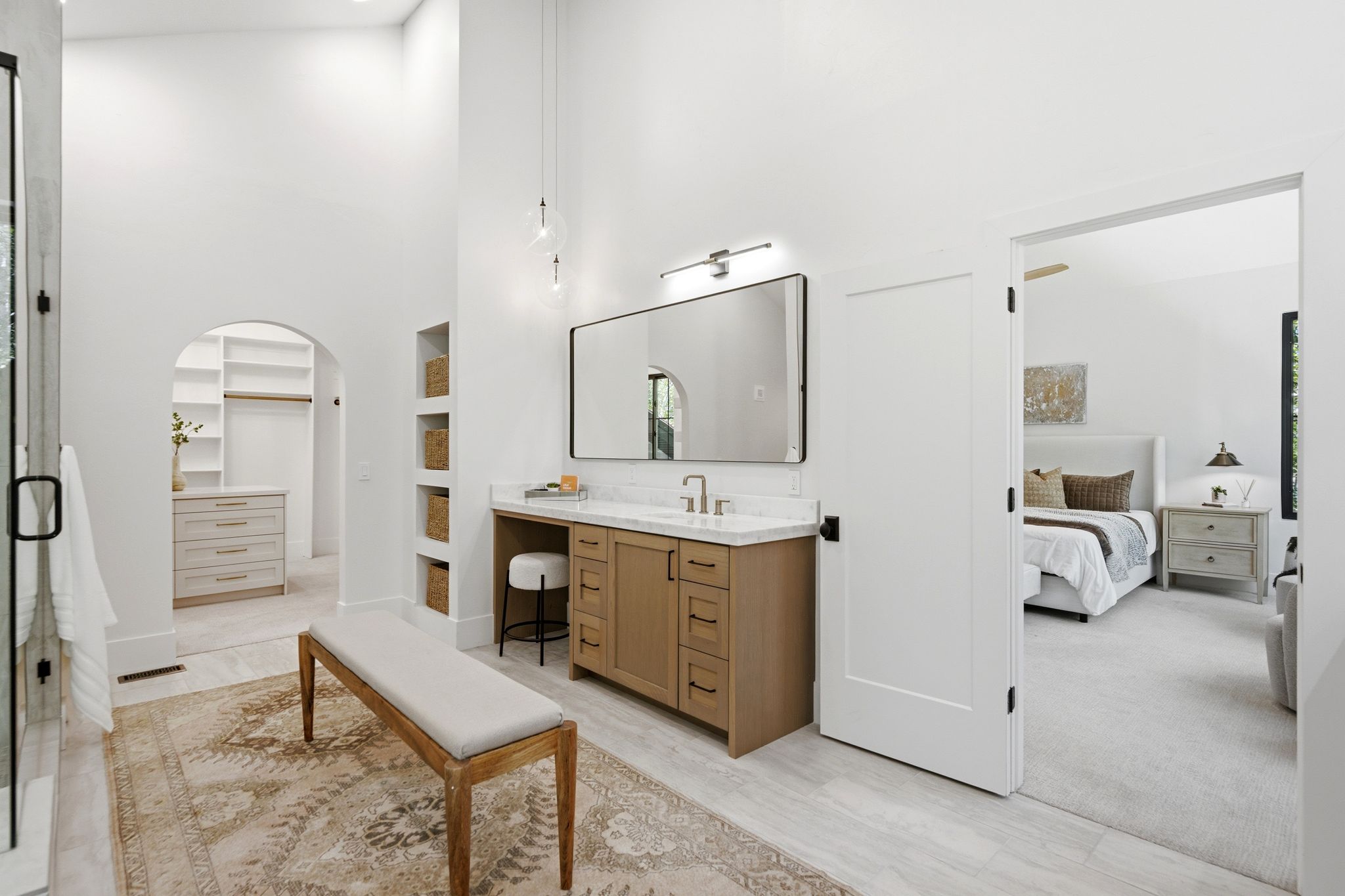 Spacious bathroom featuring a single vanity with wood cabinetry and a light-toned countertop, a large framed mirror, and integrated shelving niches