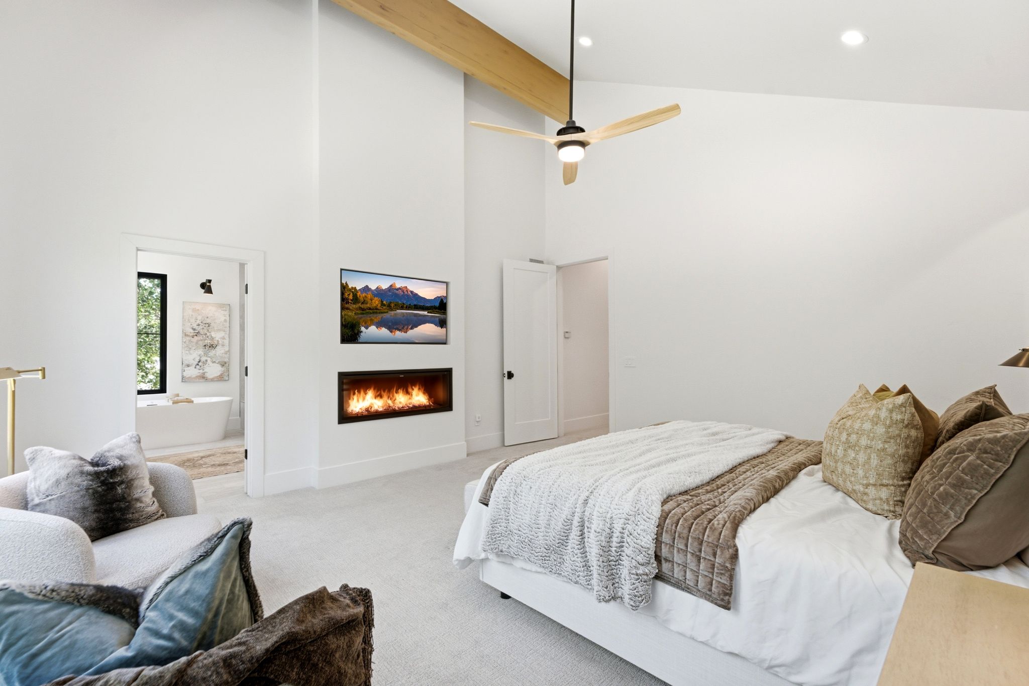 Spacious room featuring vaulted ceilings with exposed wood beams, a sleek linear fireplace, and an integrated ceiling fan