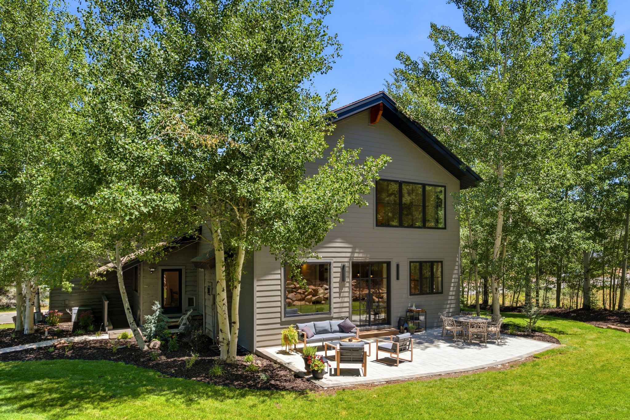 Contemporary exterior featuring gray siding, a dark-trimmed gable roof, and multiple large windows