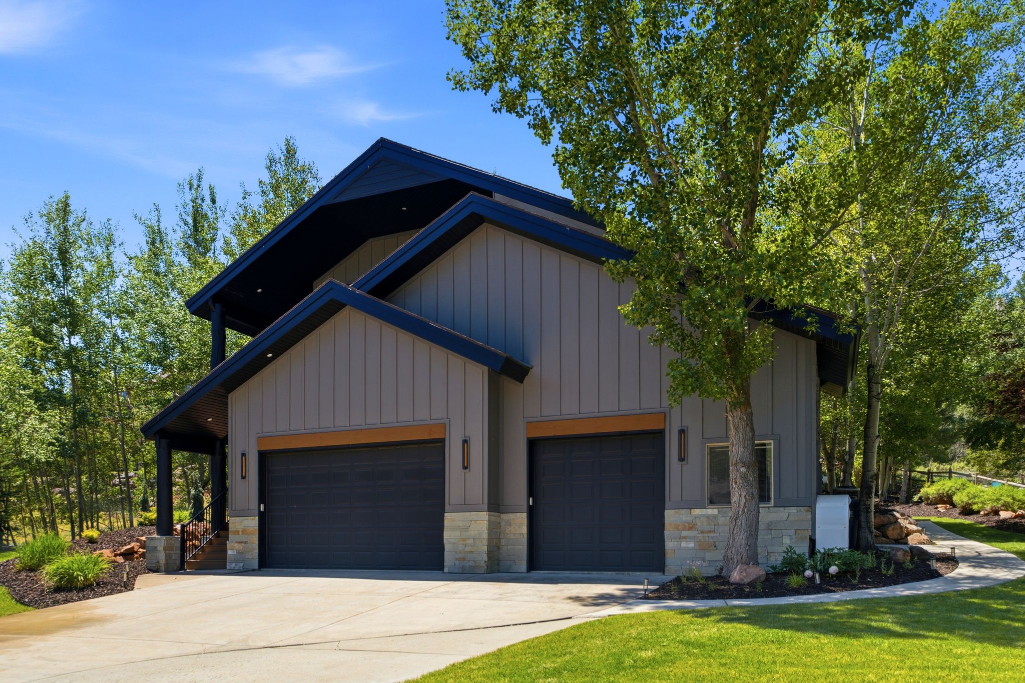 Modern exterior with vertical board siding, stone accents, and two garage bays