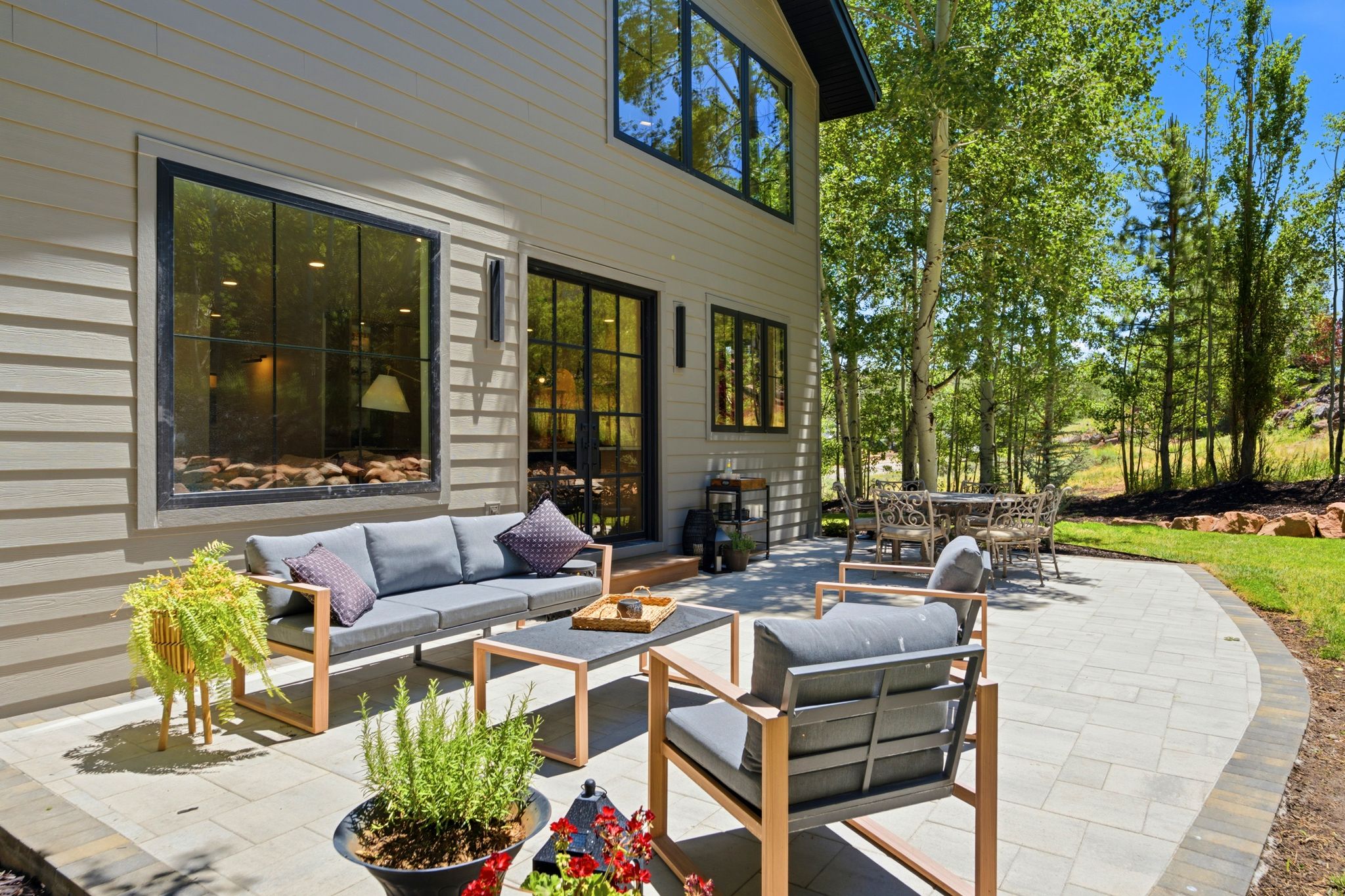 Expansive paver patio with a curved edge, surrounded by mature trees