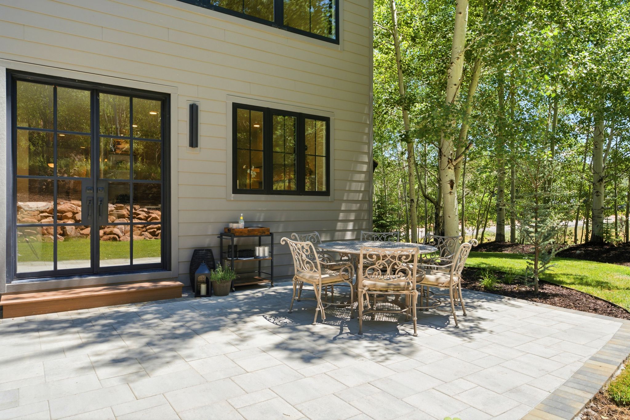 Expansive paver patio with a stone-finish border, directly accessible from the interior via black-framed French doors