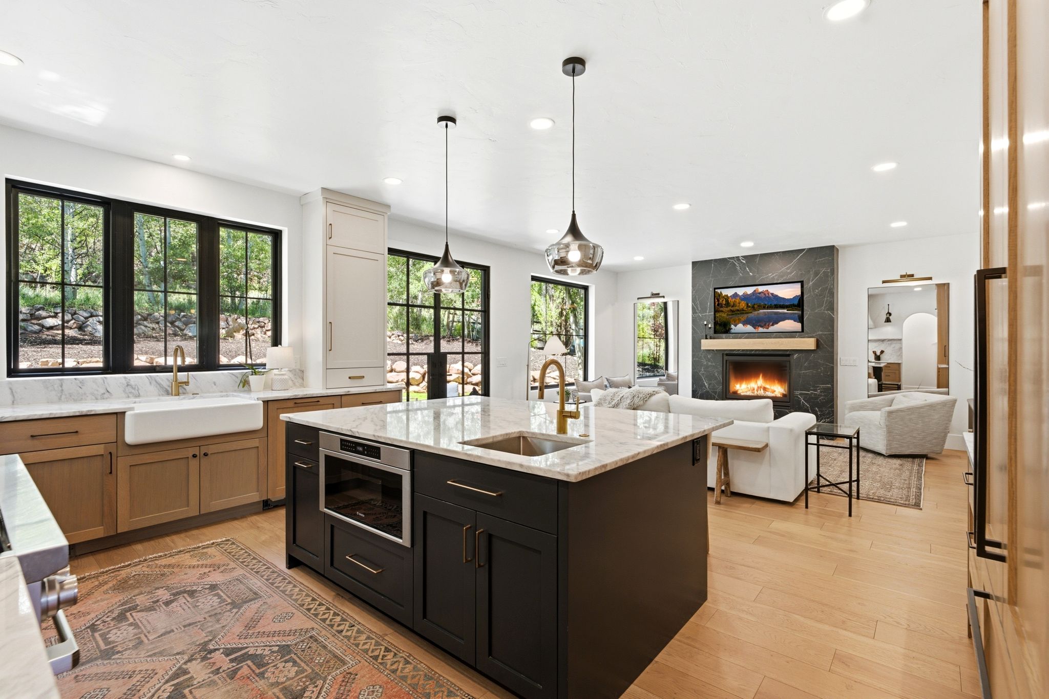 Open-concept kitchen featuring a large central island with integrated microwave, gold-finish faucet, and granite countertop