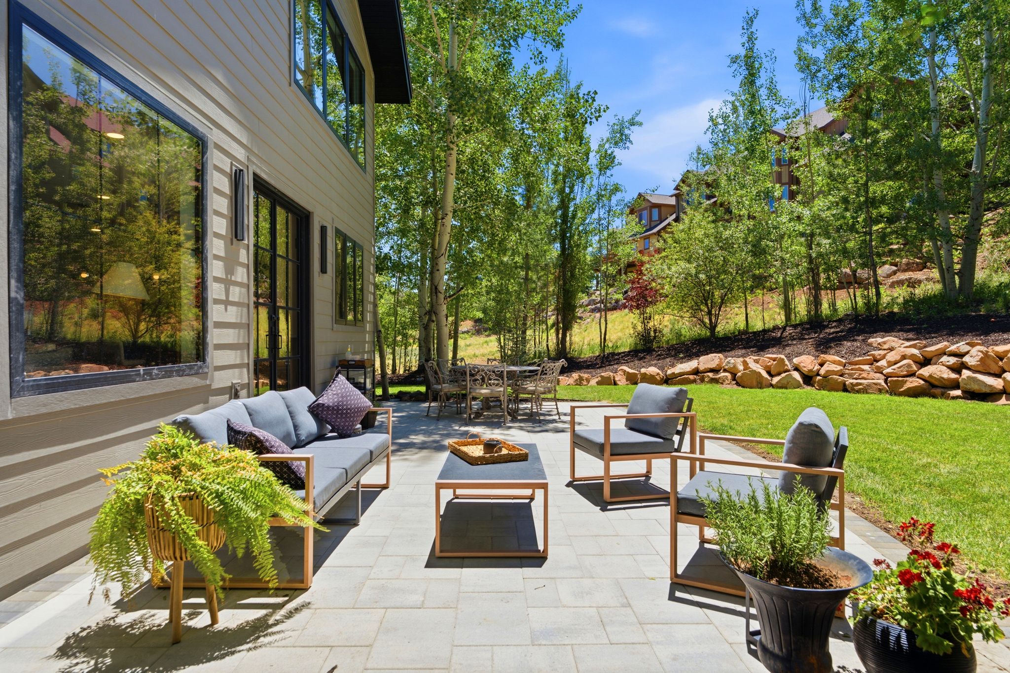 Expansive paver patio with a stone retaining wall and lush green lawn