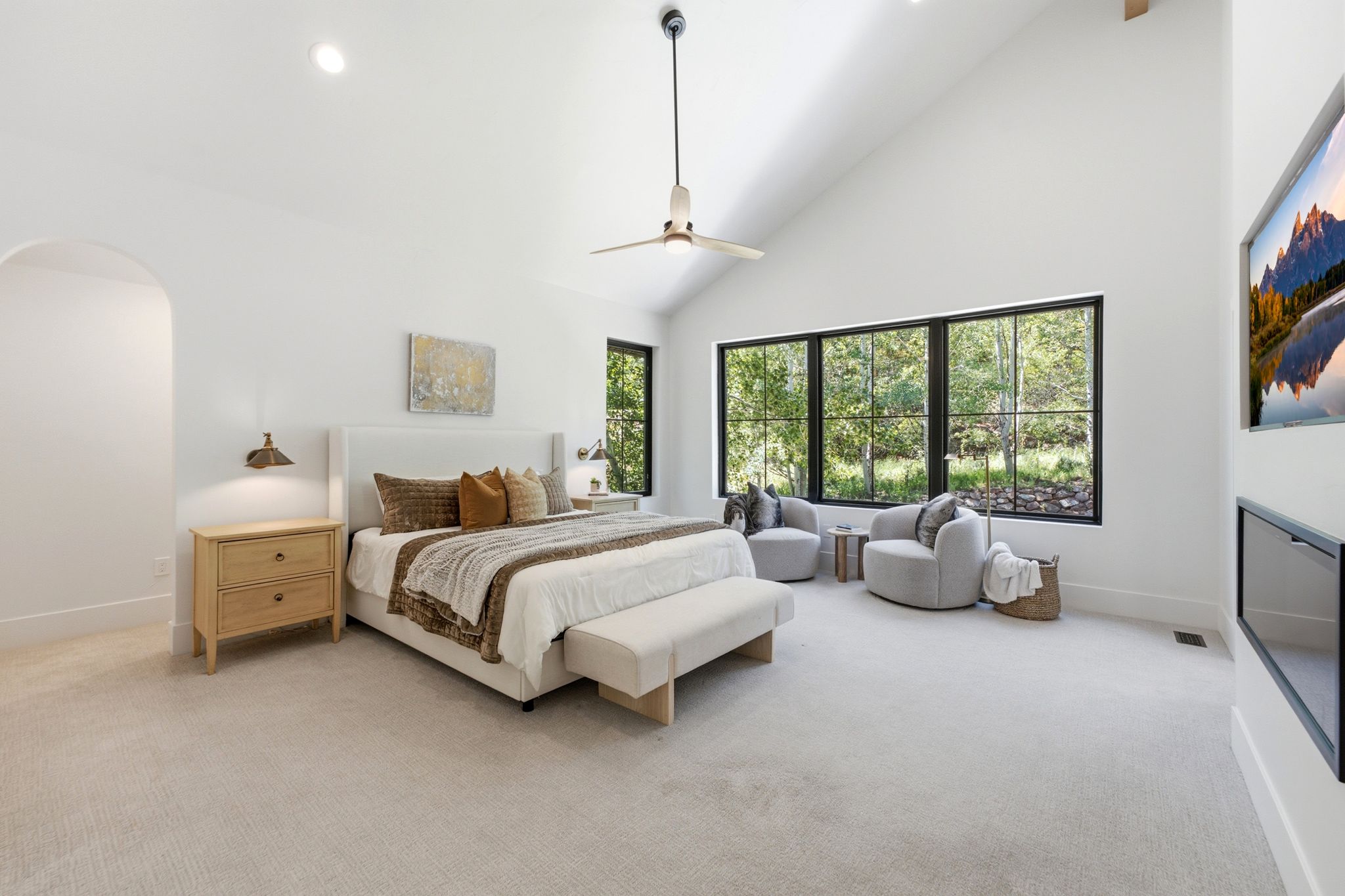 Spacious room featuring vaulted ceilings, a contemporary ceiling fan, and expansive windows with dark frames